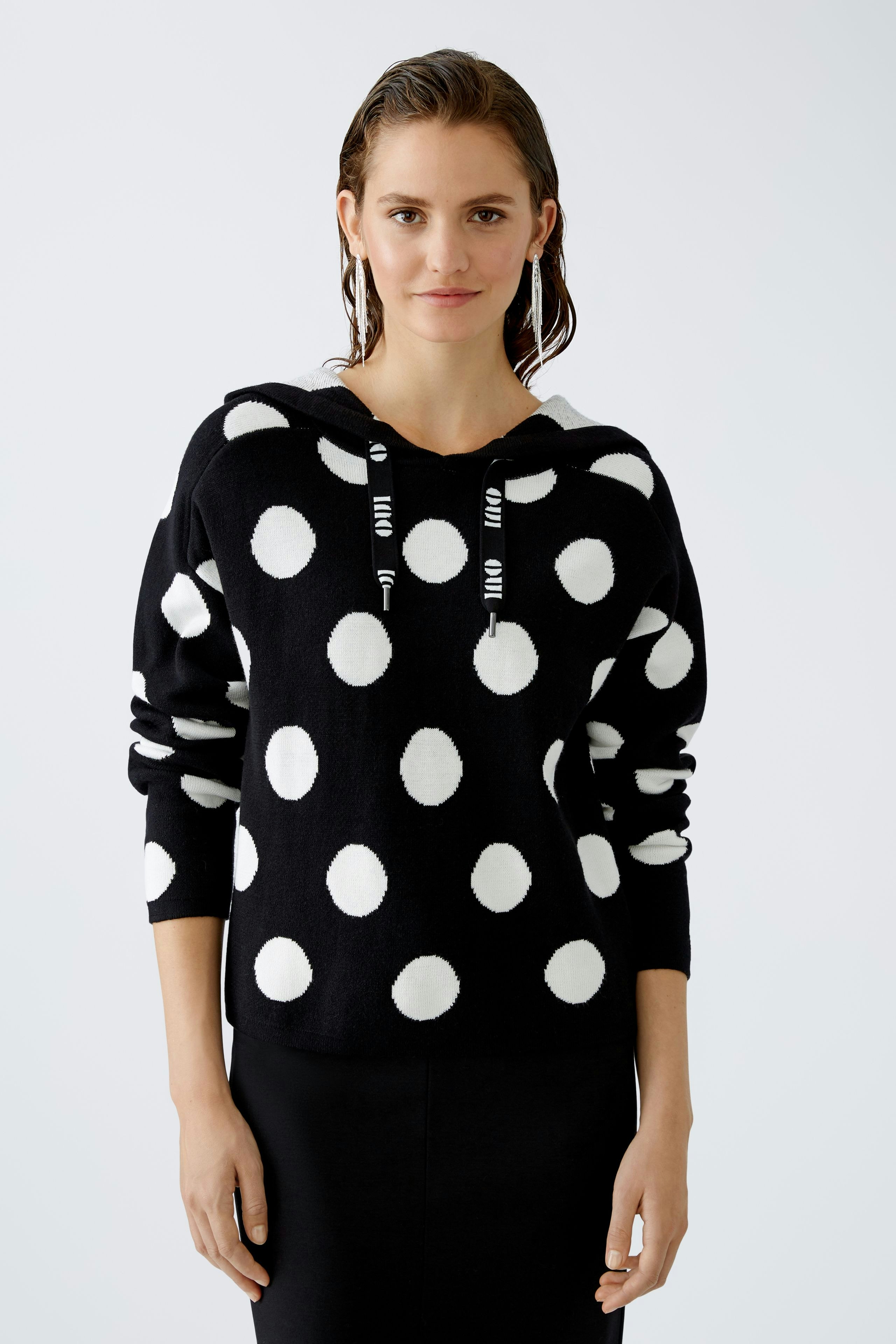 Stylish women's hoodie: A woman in a black pullover with white polka dots, exuding casual elegance.