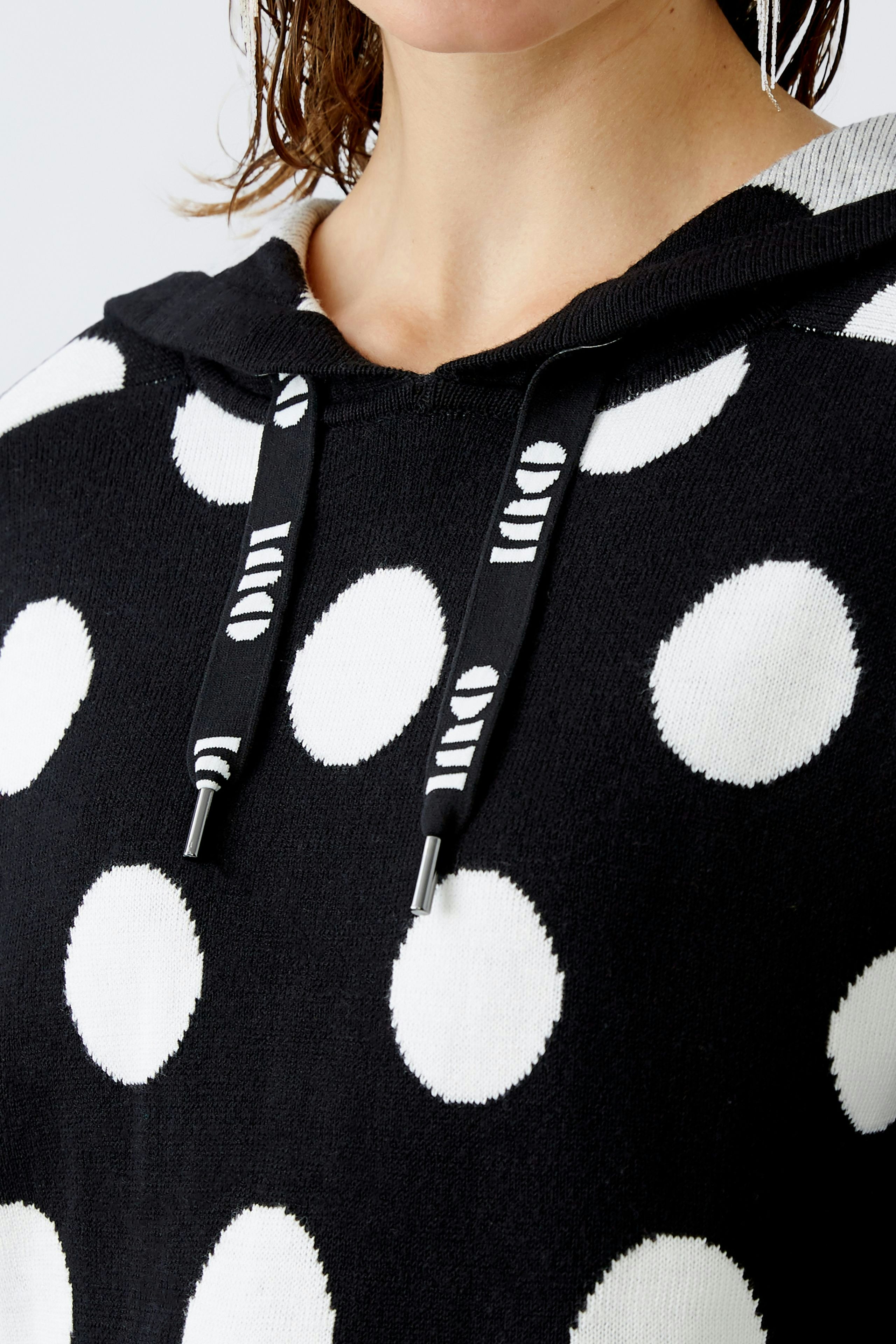 Stylish women's pullover: Close-up of a woman in a black and white polka dot hoodie.