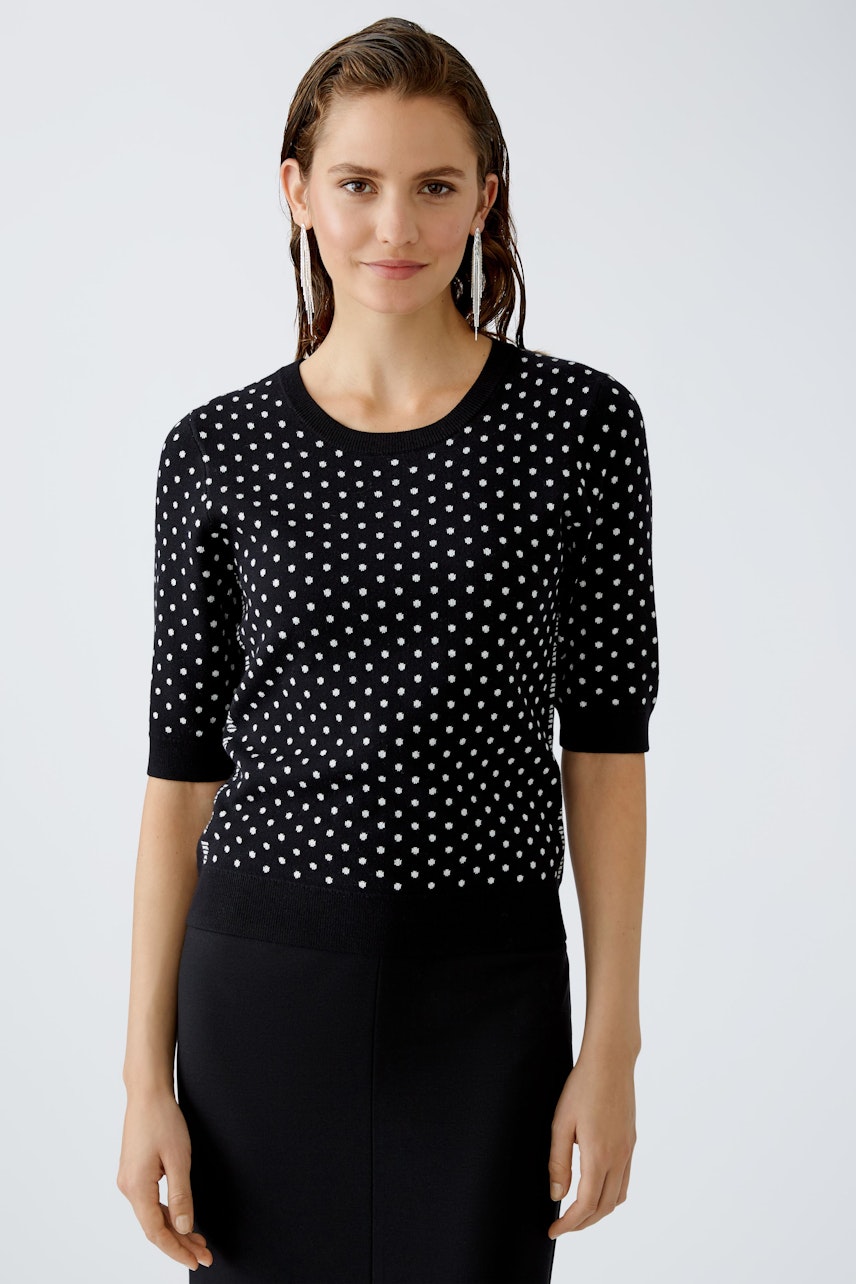 Modern women's pullover: A woman in a black polka dot pullover exudes confidence and style.