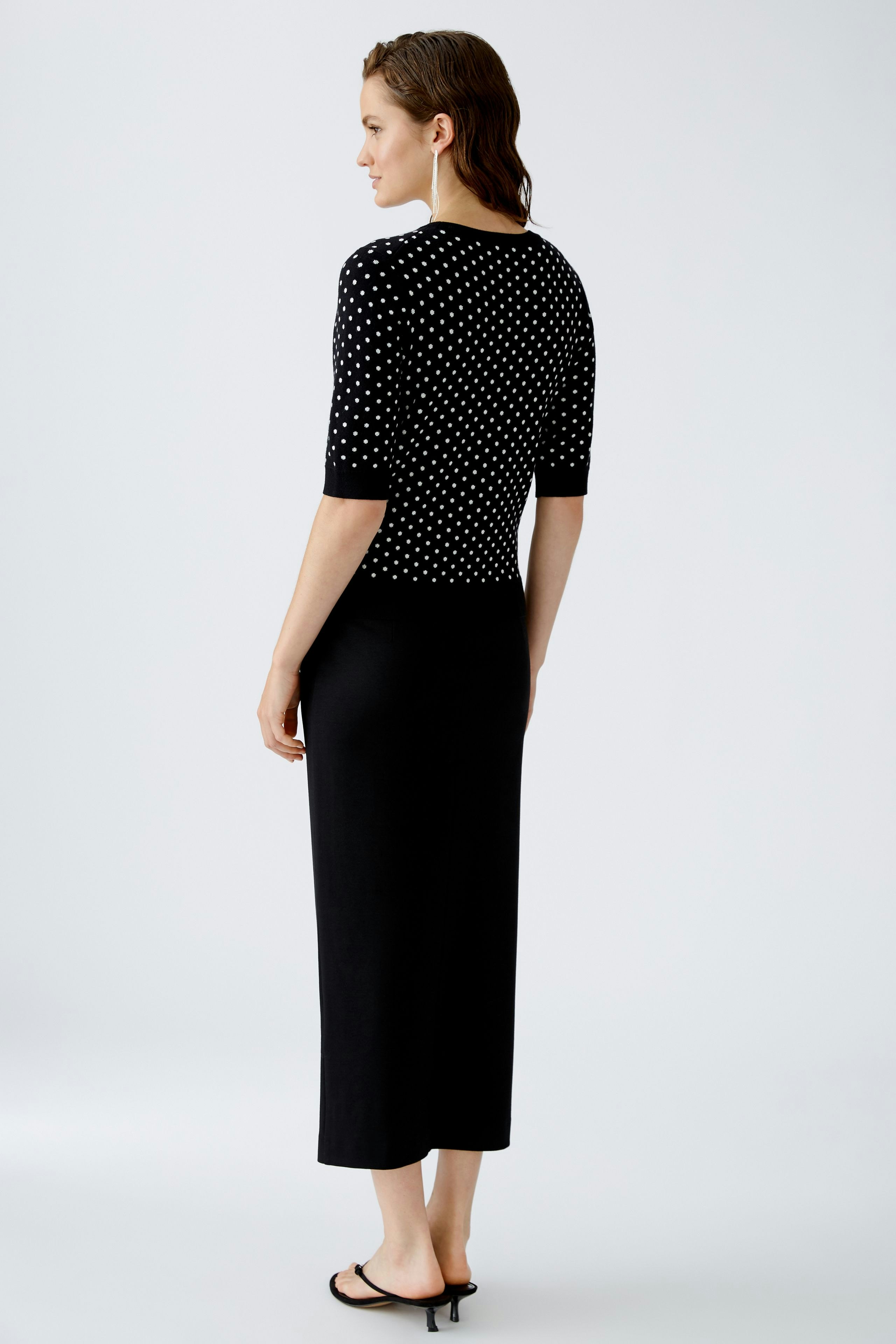 Stylish women's pullover: A woman in a black polka dot pullover, showcasing a chic and modern look.