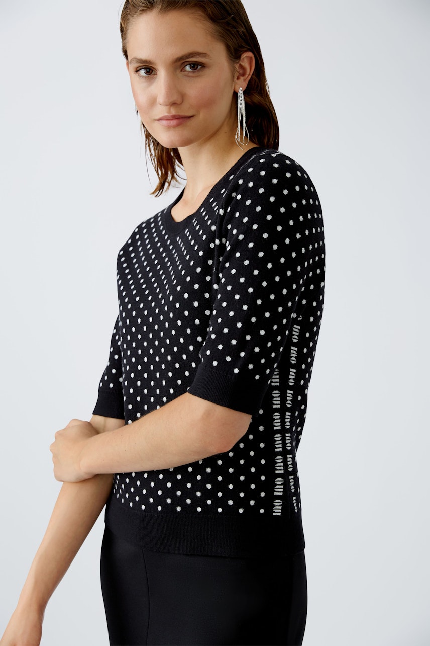 Stylish women's pullover: A woman in a black polka dot pullover with short sleeves.