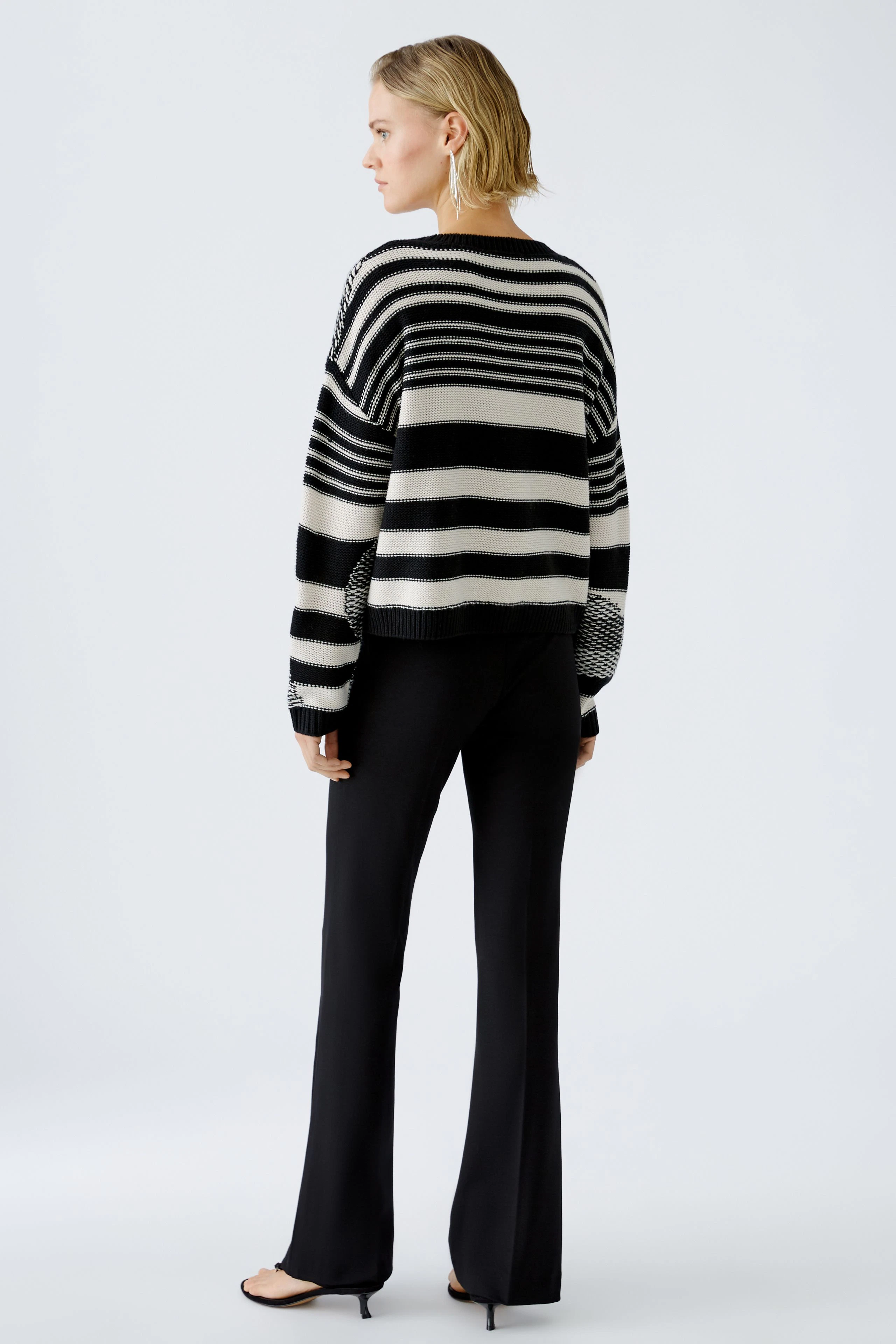 Stylish women's pullover: A woman in a striped black and white pullover, showcasing a modern look.