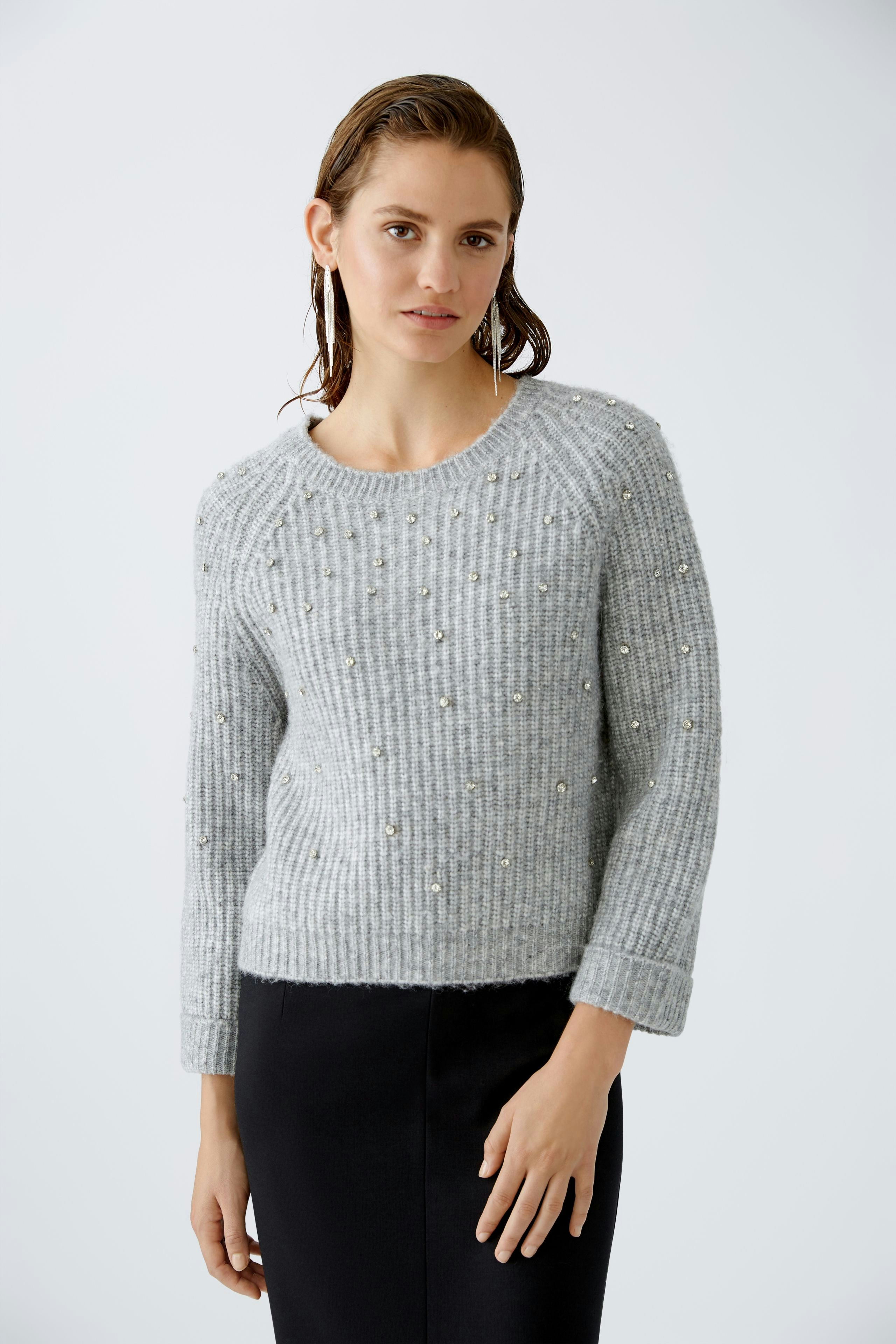 Eleganter Damen-Pullover: Frau in grauem Strickpullover mit Perlen, kombiniert mit einem schlichten Rock.