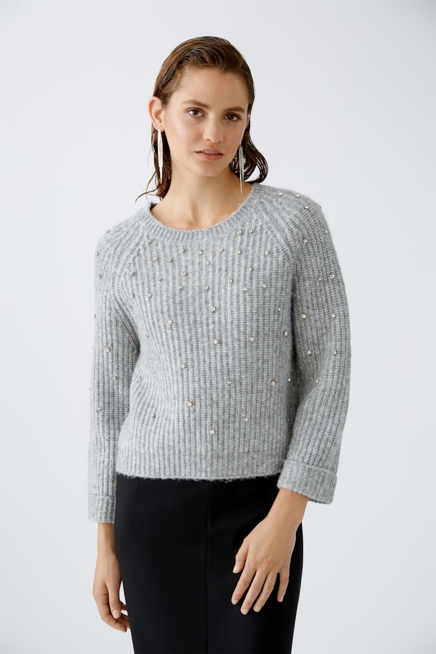 Stylish women's pullover: A woman in a light gray pullover with embellishments, exuding elegance.