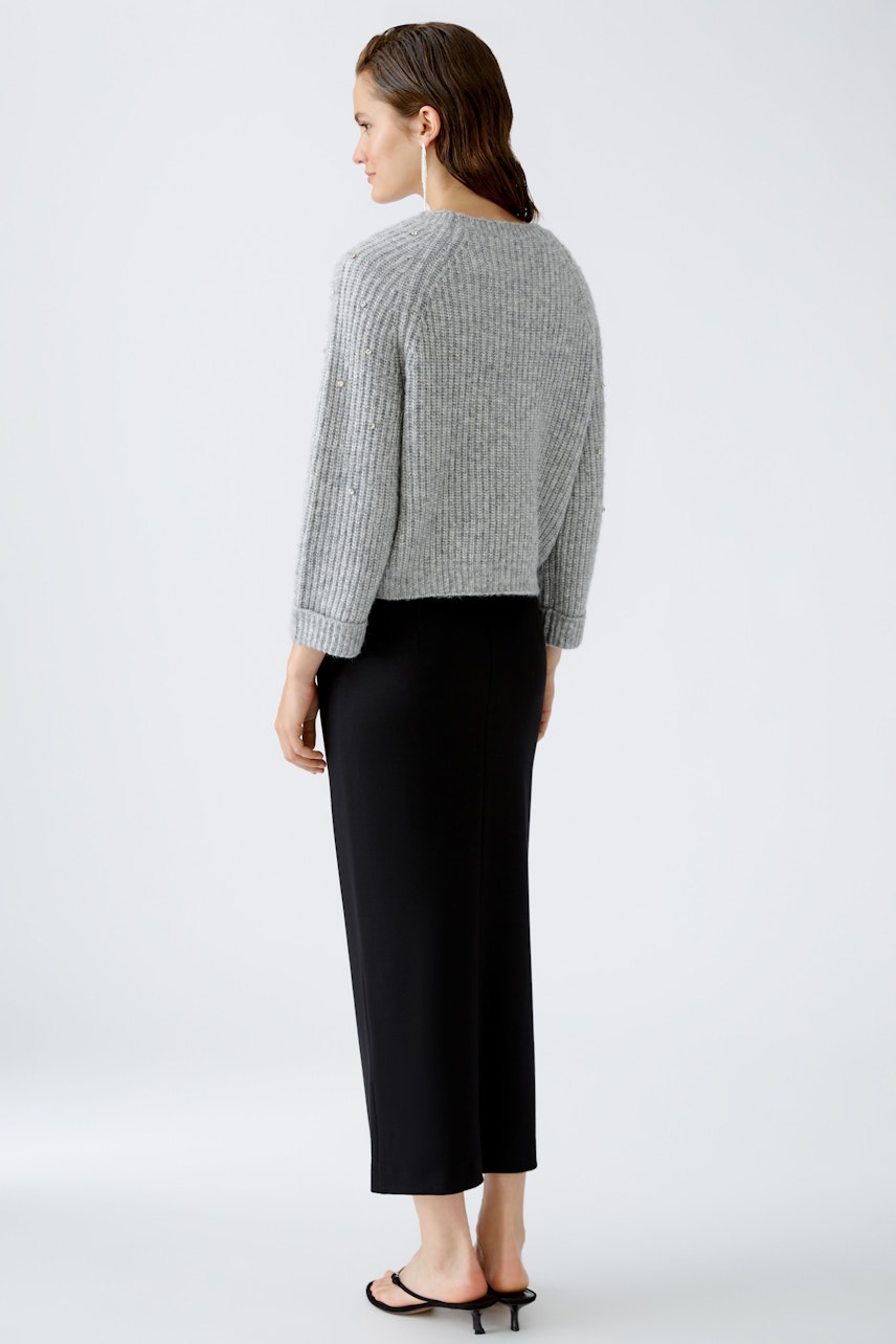 Stylish women's pullover: A woman in a cozy gray pullover paired with a sleek black skirt.