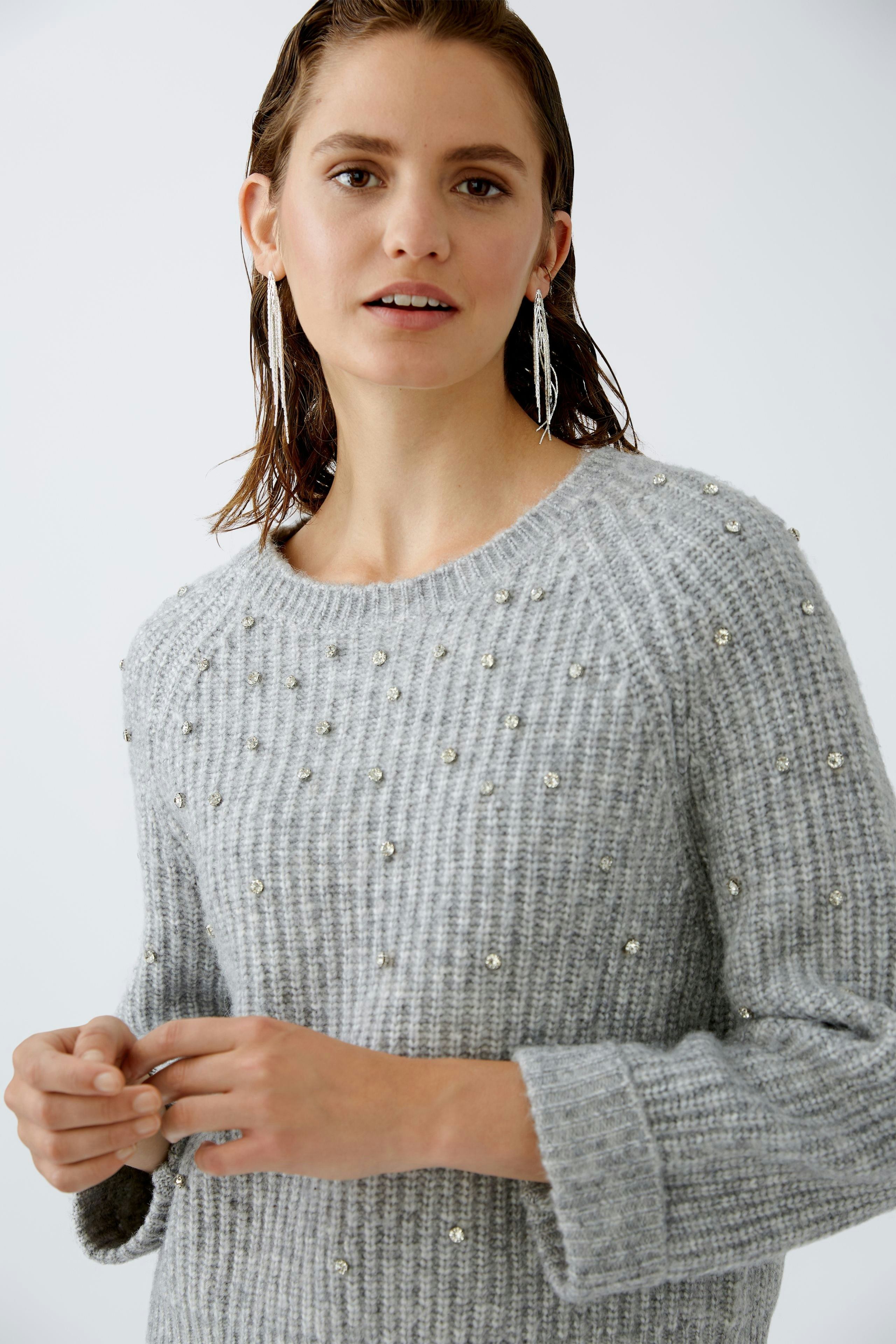Eleganter Damen-Pullover: Frau in grauem Strickpullover mit Perlen, lässig und stilvoll.