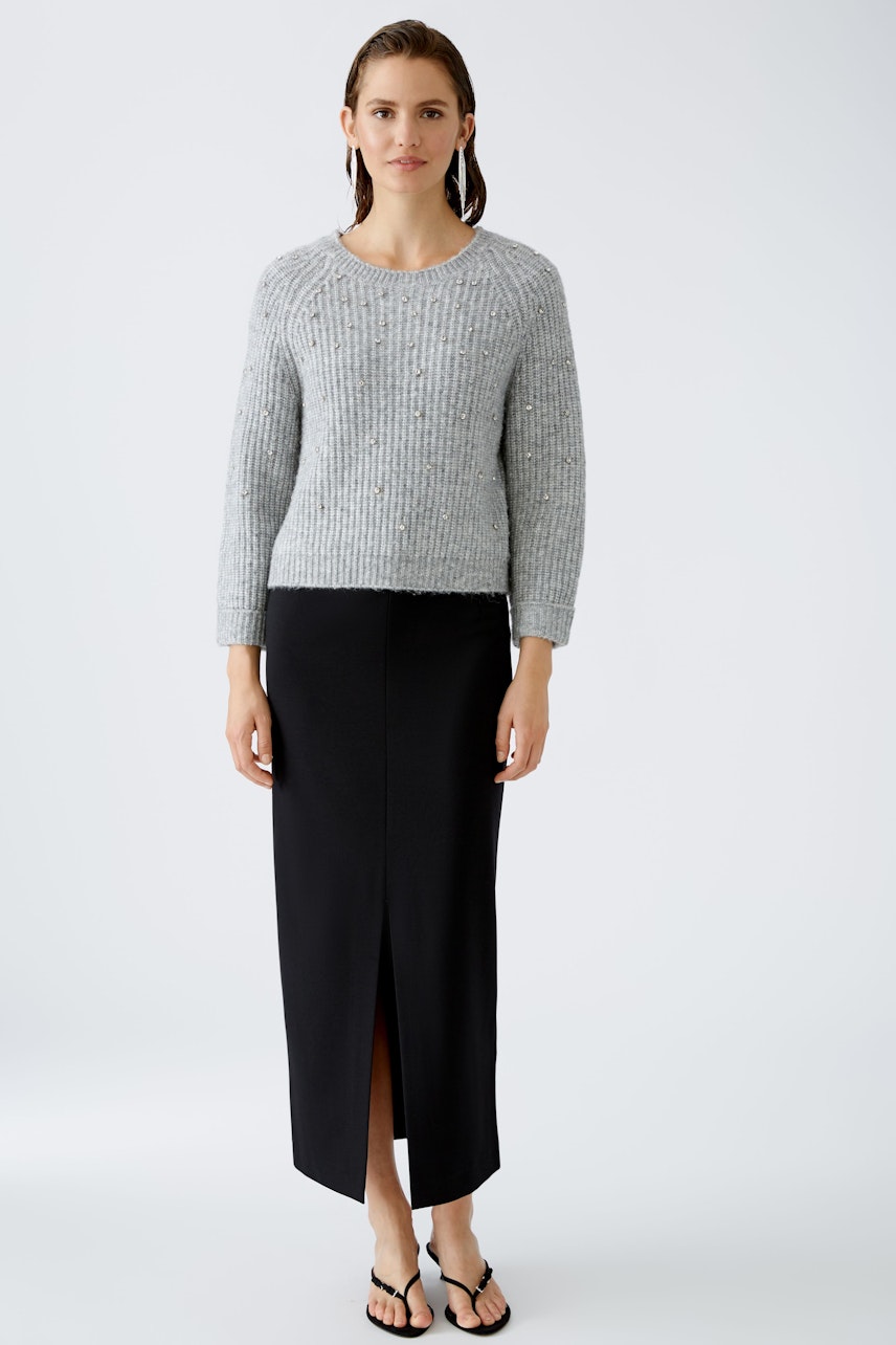 Modern women's pullover: A woman in a gray ribbed pullover paired with a sleek black skirt.