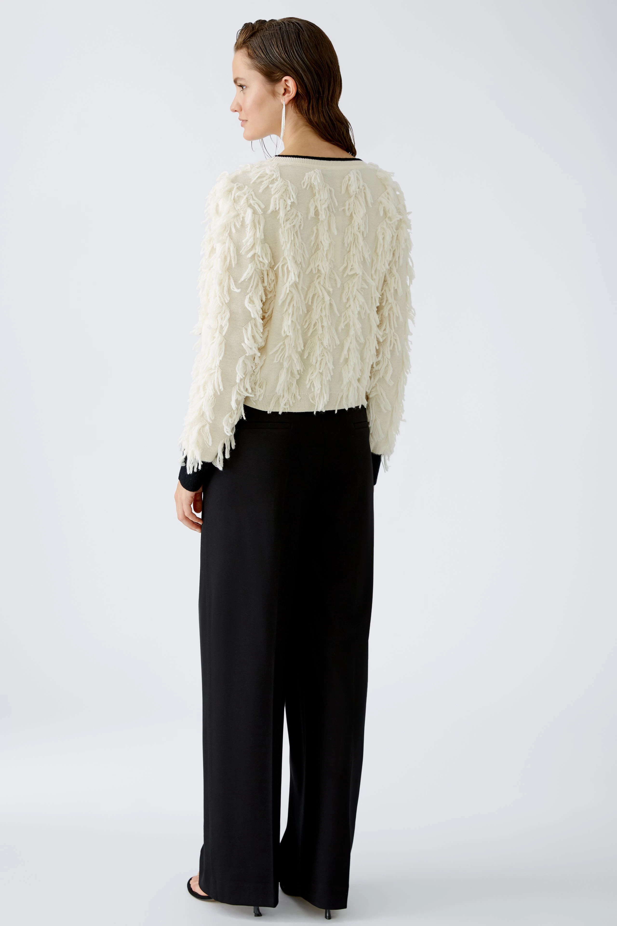 Stylish women's pullover: A woman in a textured cream pullover paired with black trousers.