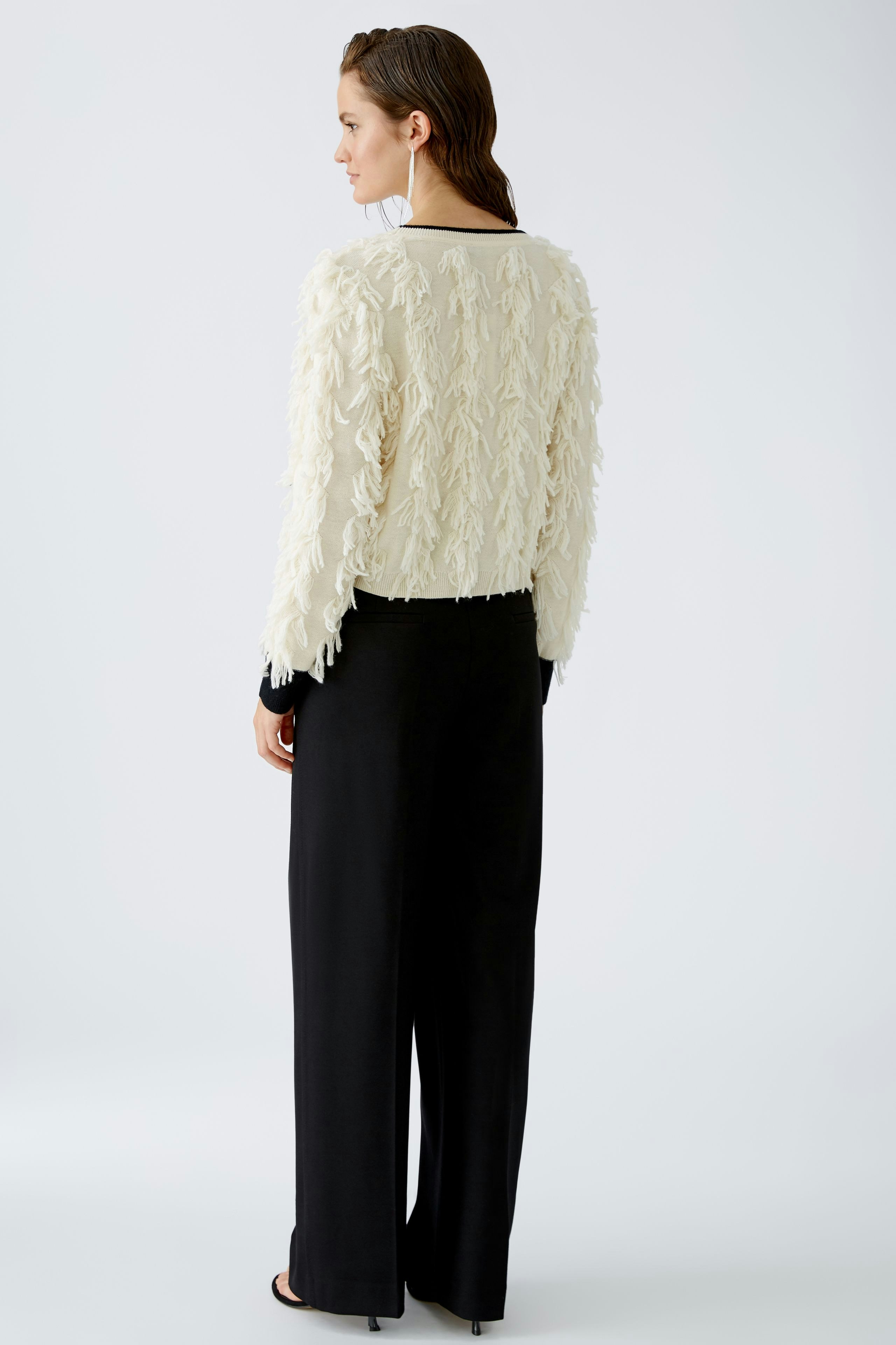 Stylish women's pullover: A woman in a textured cream pullover paired with black trousers.