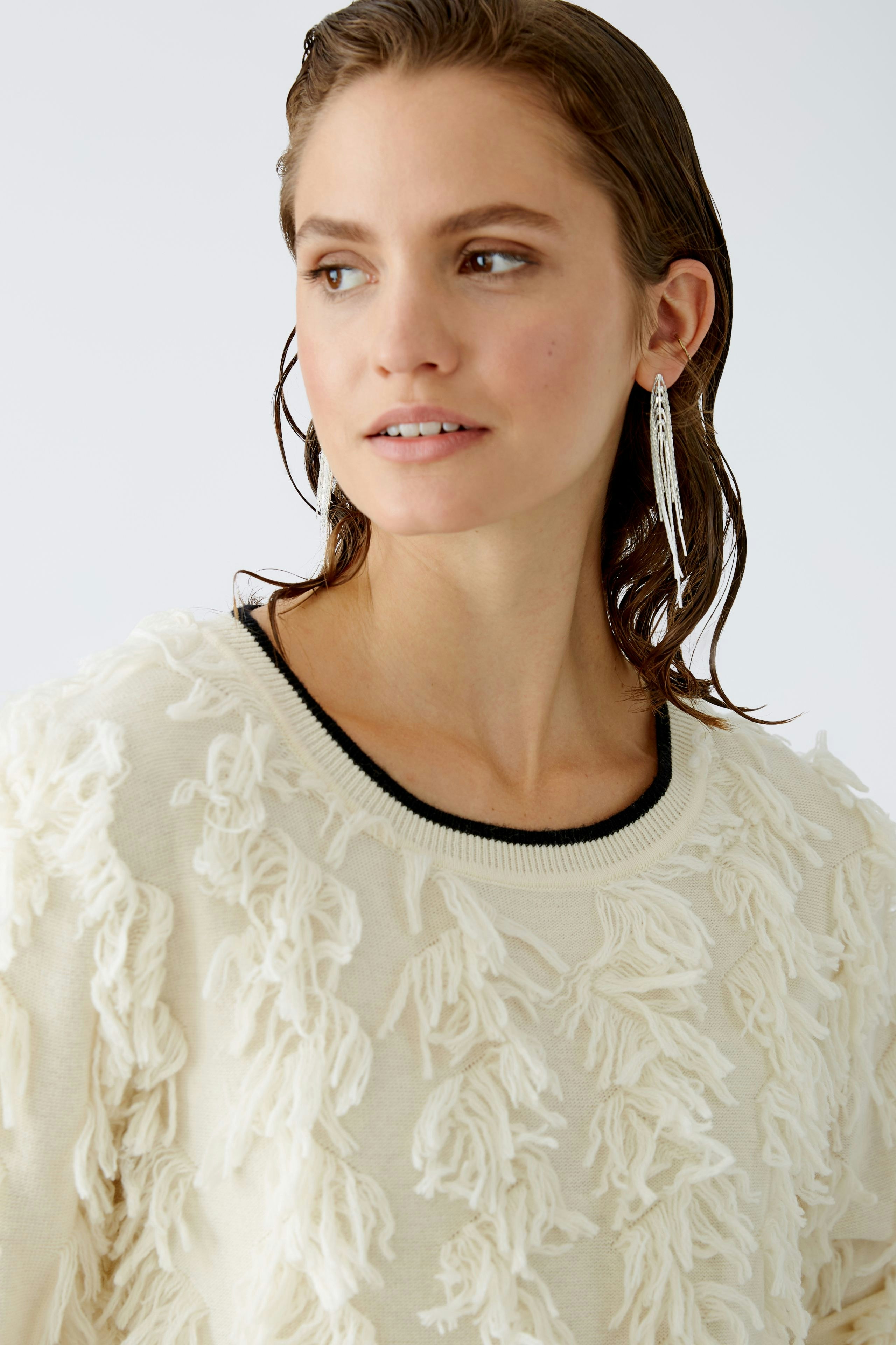 Modern women's pullover: A woman in a cream pullover with fringe details, exuding effortless style.