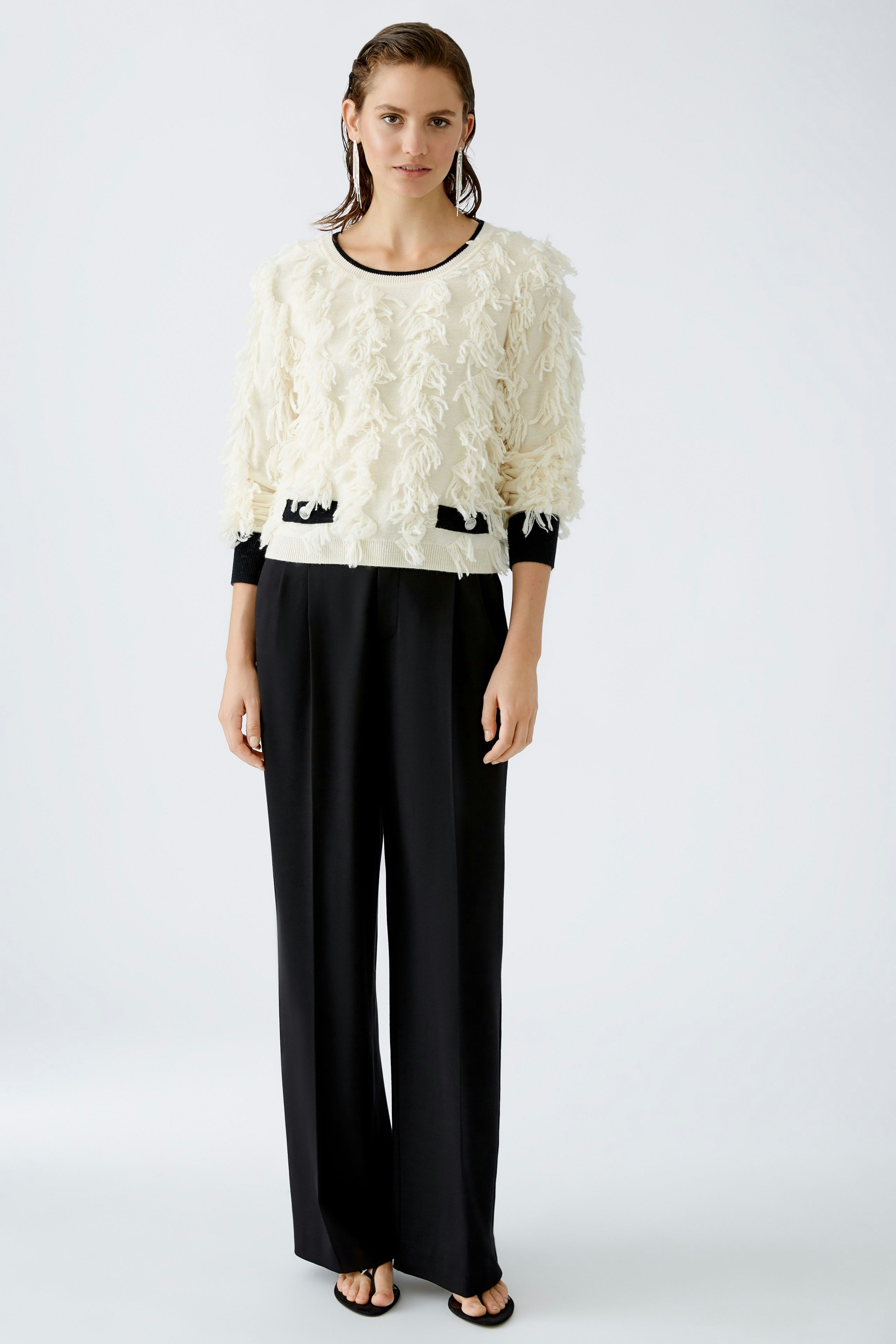 Modern women's pullover: A woman in a fluffy white pullover with black accents stands confidently.