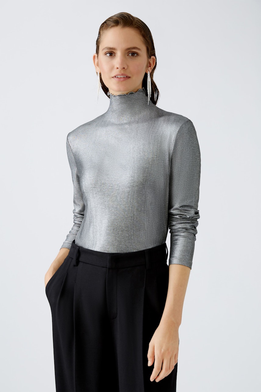 Stylish long-sleeve shirt: Woman in a shimmering silver top paired with elegant trousers.