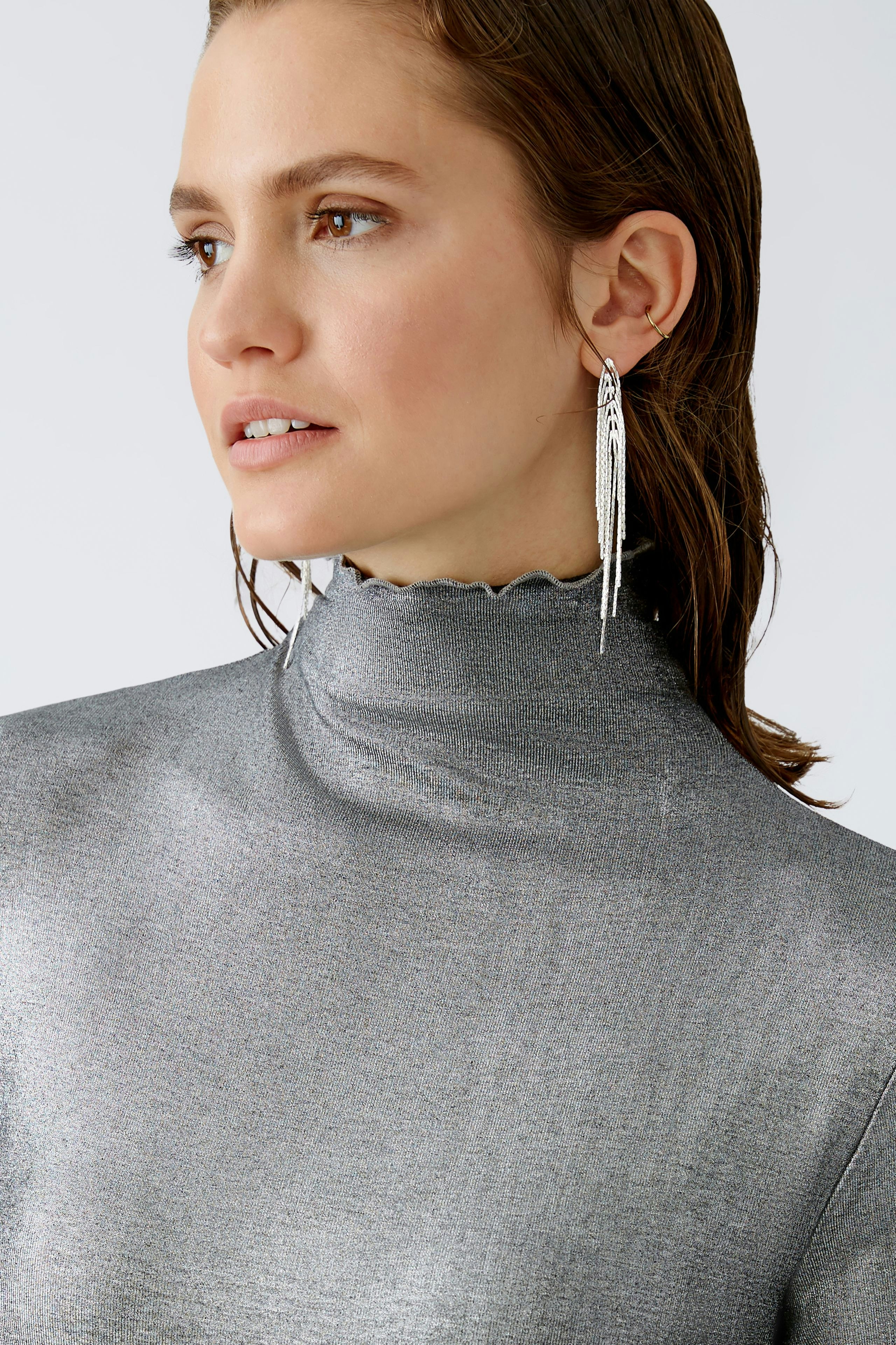 Stylish long-sleeve shirt: Woman in a shimmering silver pullover with a high neck, exuding elegance.