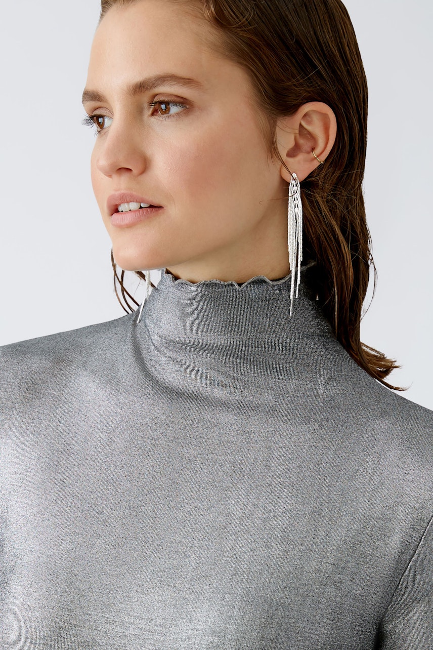 Stylish long-sleeve shirt: Woman in a shimmering silver pullover with a high neck, exuding elegance.