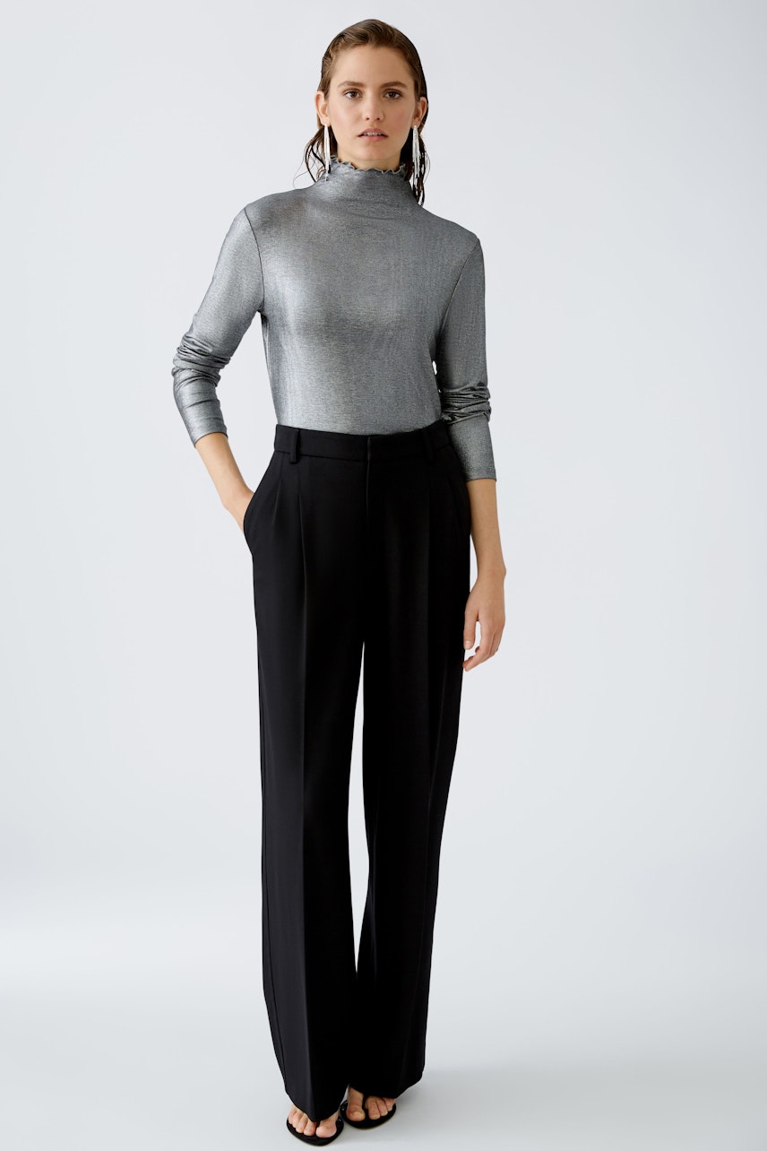 Stylish long-sleeve shirt: A woman in a shiny silver pullover paired with elegant black trousers.