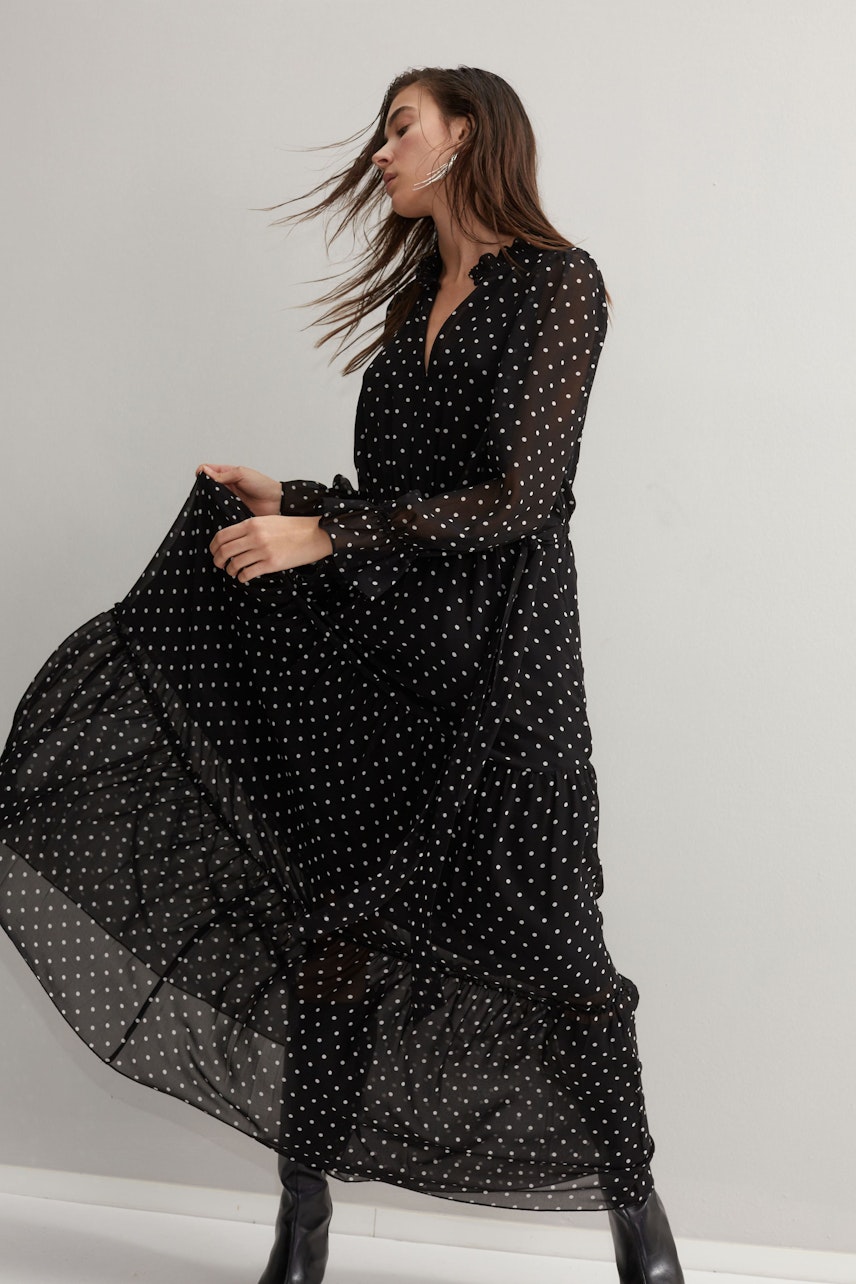 Elegant evening dress: A woman in a flowing black polka dot dress exudes grace and sophistication.