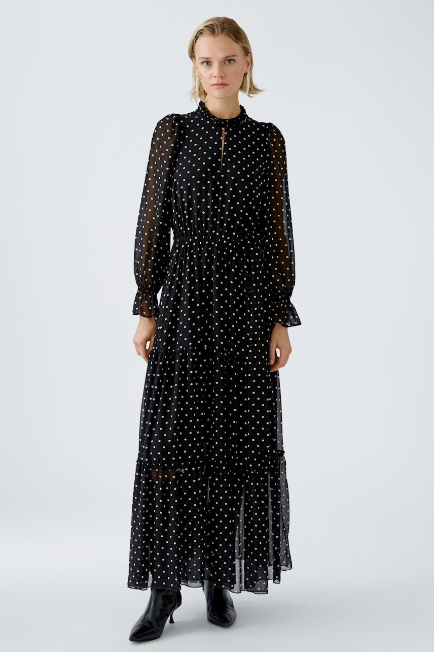 Elegant evening dress: A woman in a black polka dot maxi dress with long sleeves and a cinched waist.