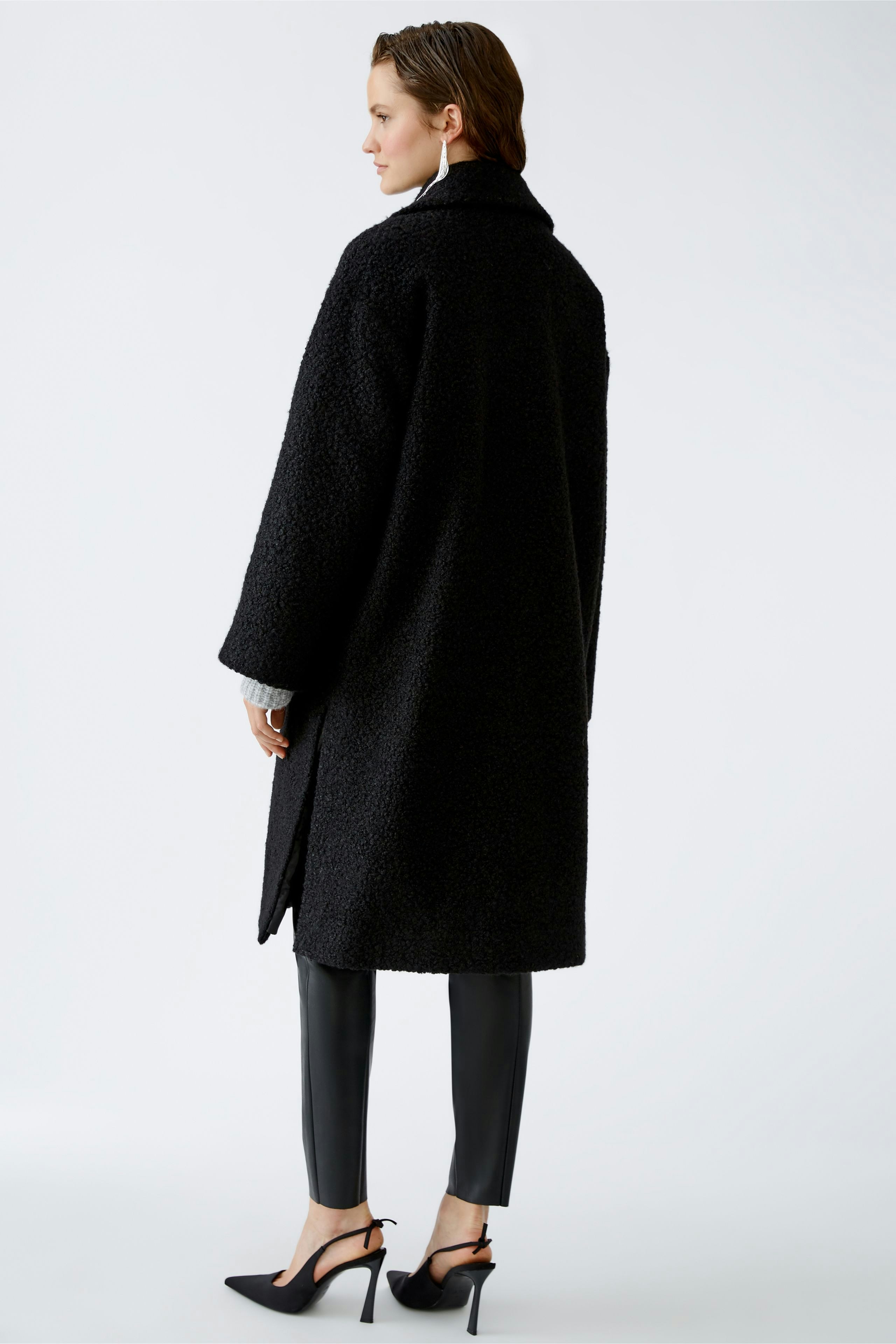 Stylish winter coat: Woman in a cozy black coat with a relaxed fit, paired with sleek pants.