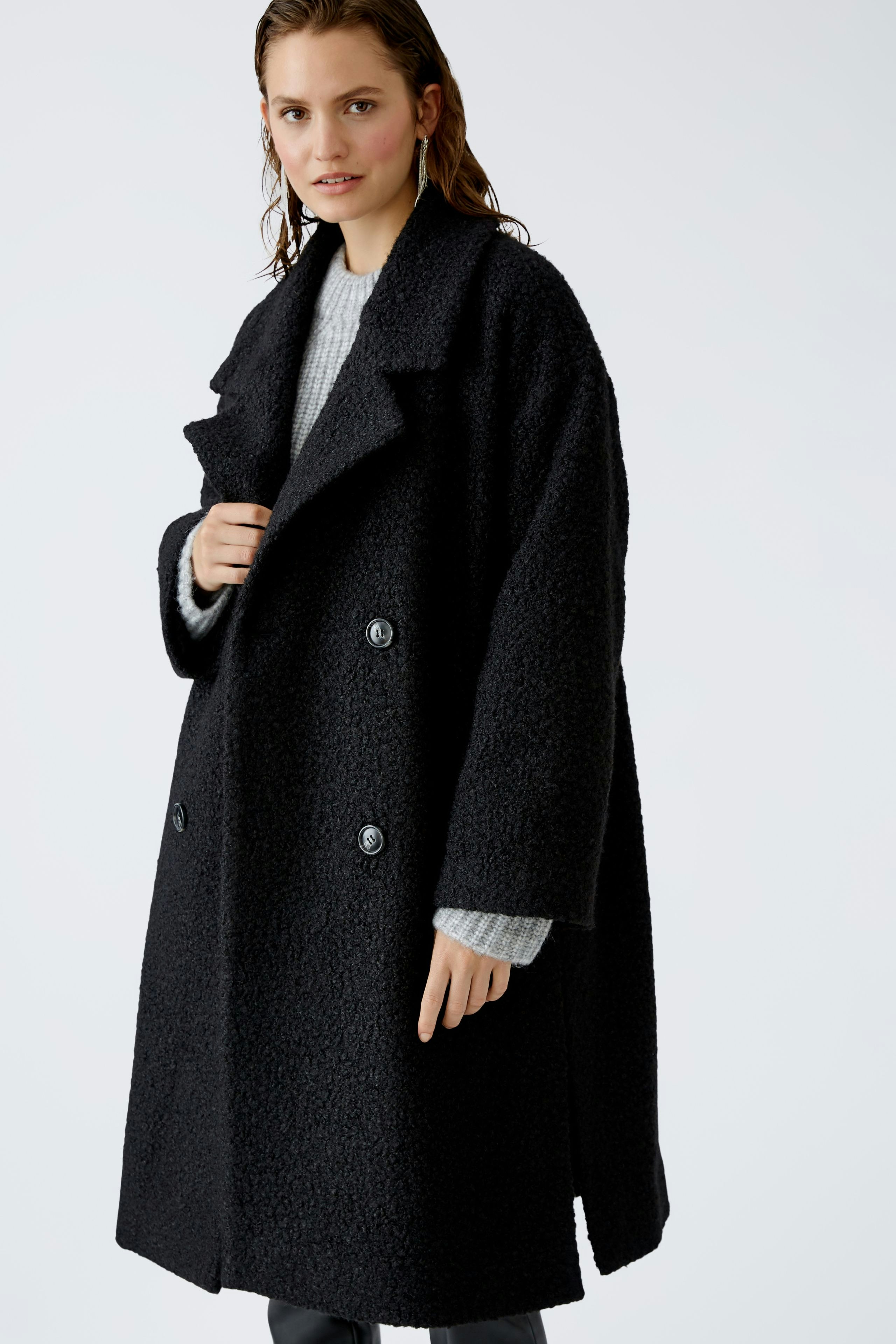 Stylish winter coat: A woman in a black oversized coat with buttons, exuding warmth and elegance.