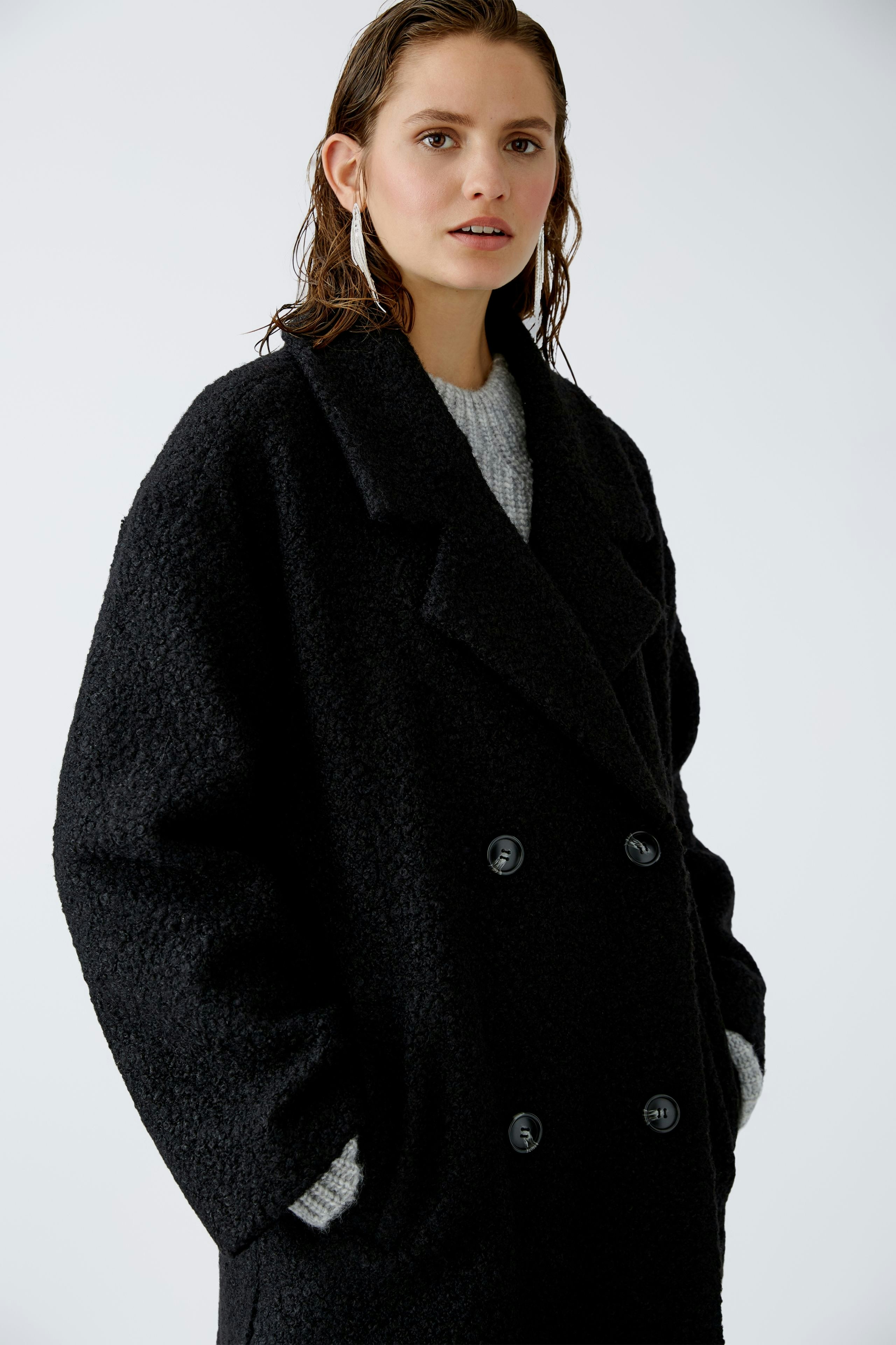 Stylish winter coat: A woman in a black double-breasted coat with a cozy texture, exuding elegance.