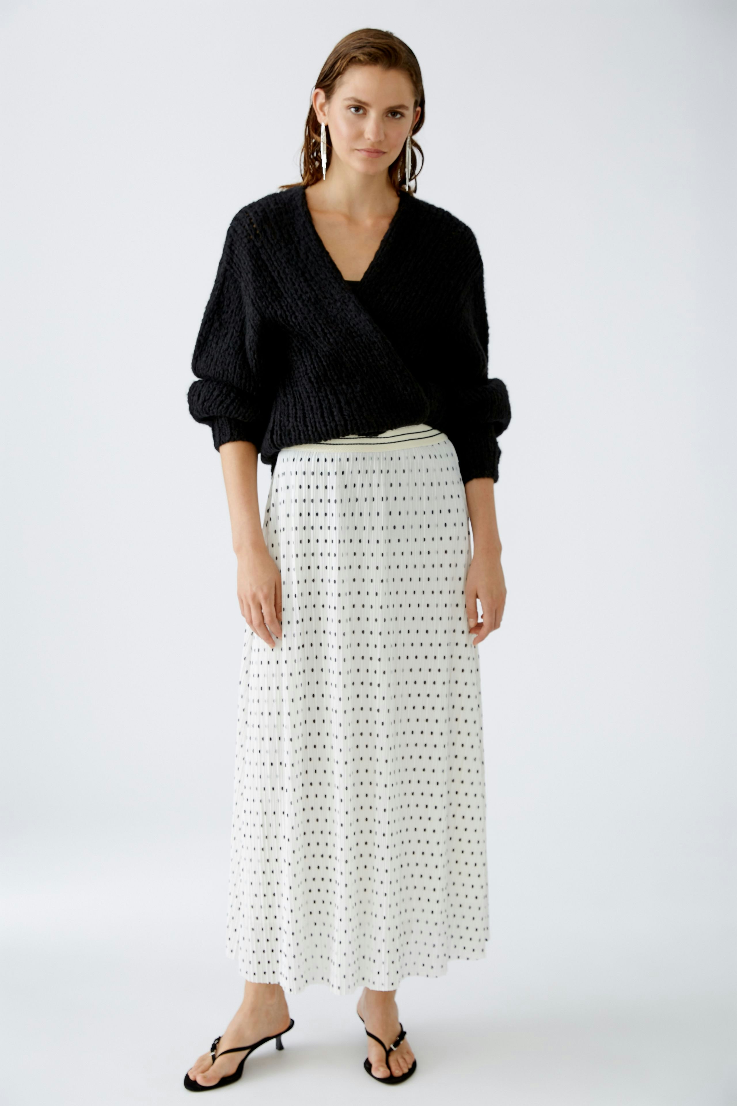 Elegant pleated skirt: A woman in a stylish white skirt with polka dots, exuding grace and sophistication.