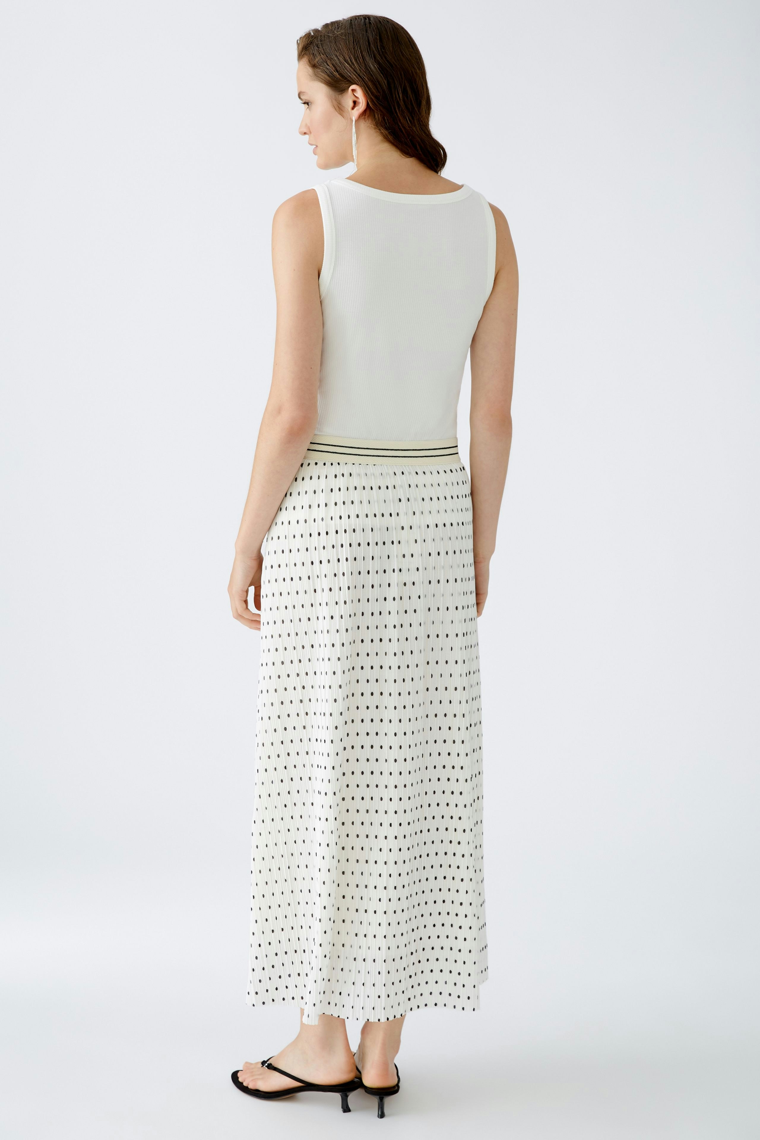 Elegant pleated skirt: Woman in a long, patterned skirt with a fitted top, showcasing a stylish silhouette.