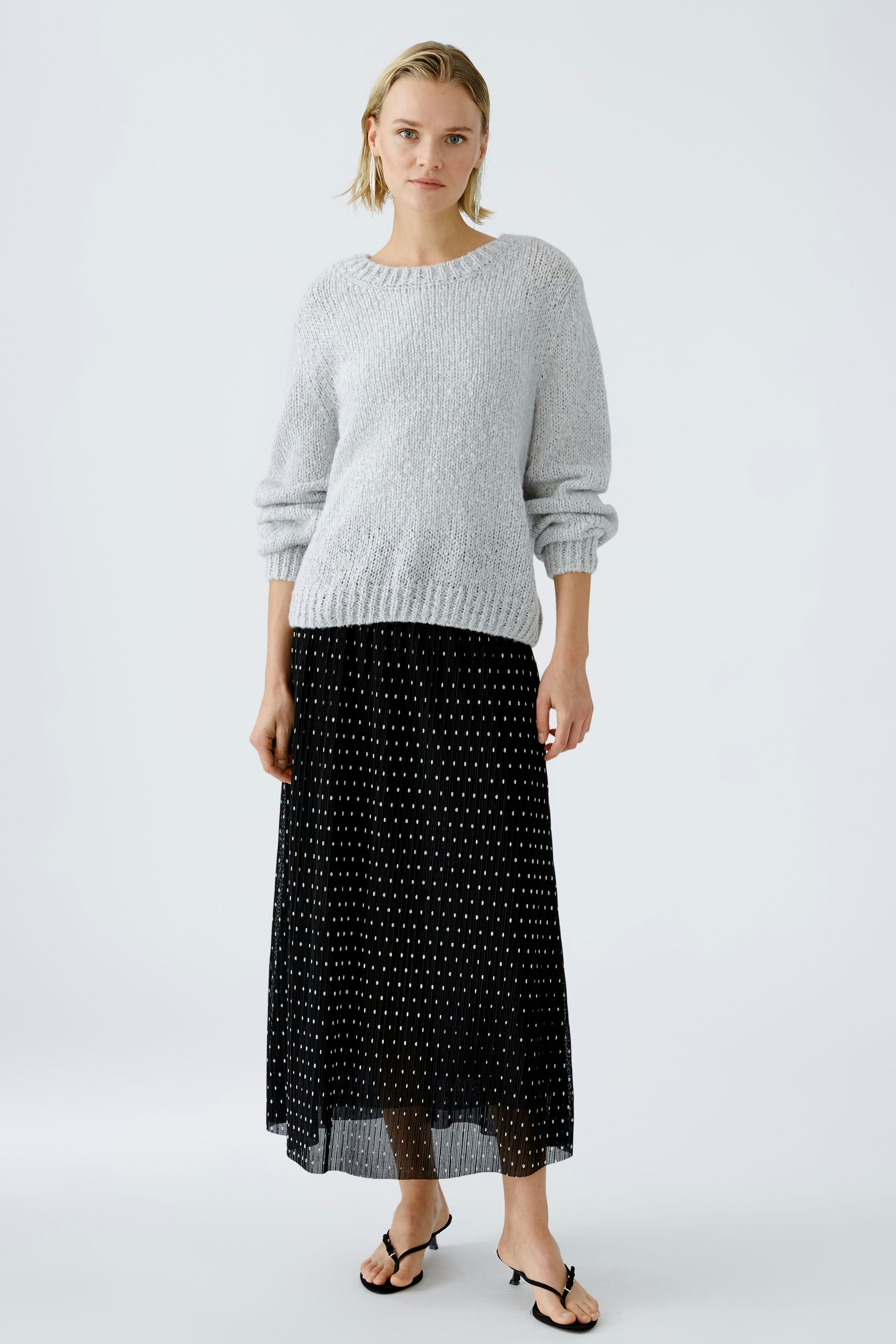 Elegant pleated skirt: A woman in a stylish black pleated skirt with a polka dot pattern.