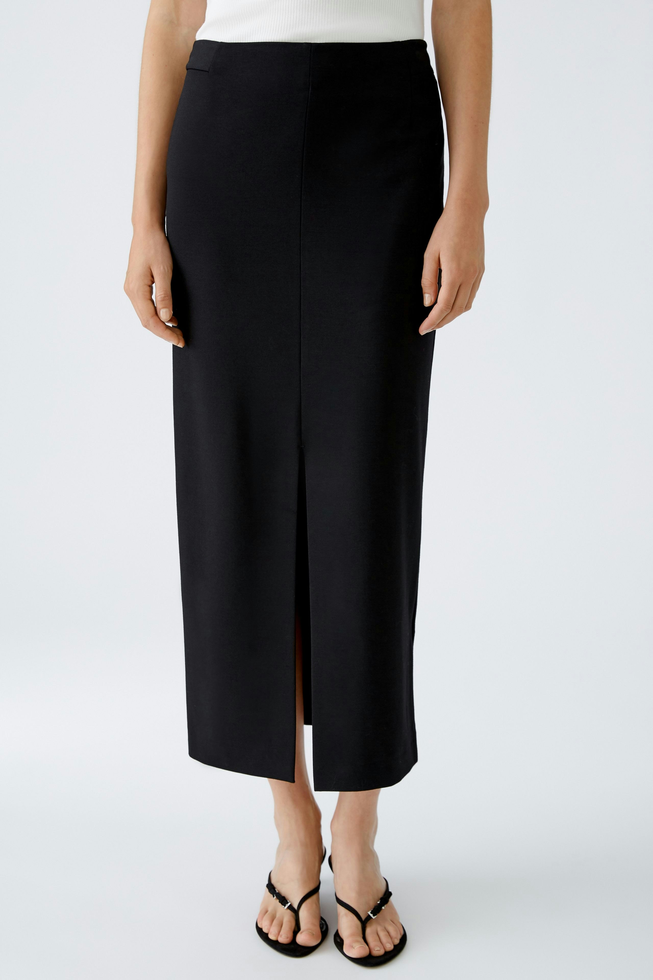 Elegant pencil skirt: Woman in a sleek black pencil skirt with a front slit, showcasing a modern silhouette.