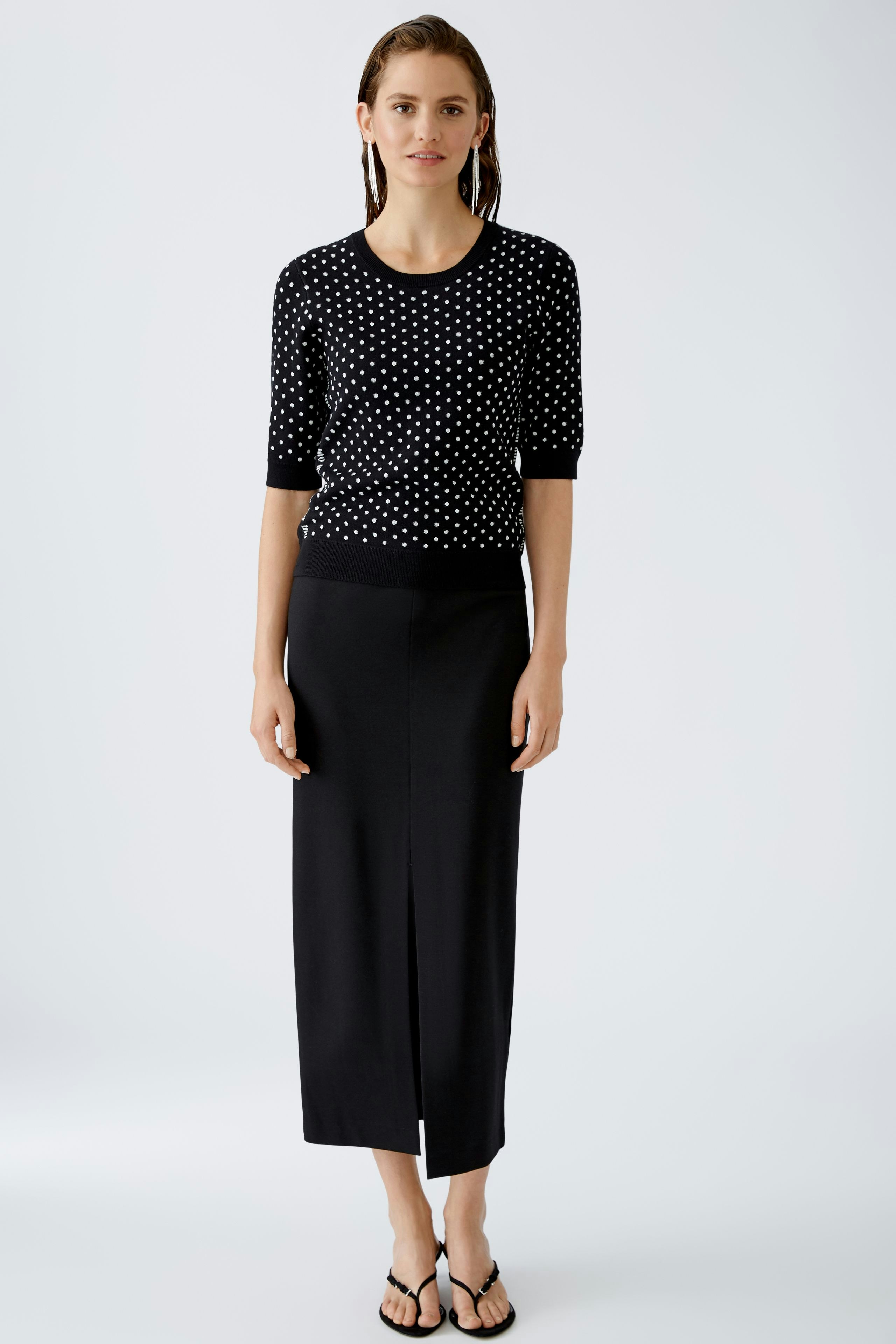 Elegant pencil skirt: A woman in a fitted black pencil skirt paired with a stylish polka dot pullover.