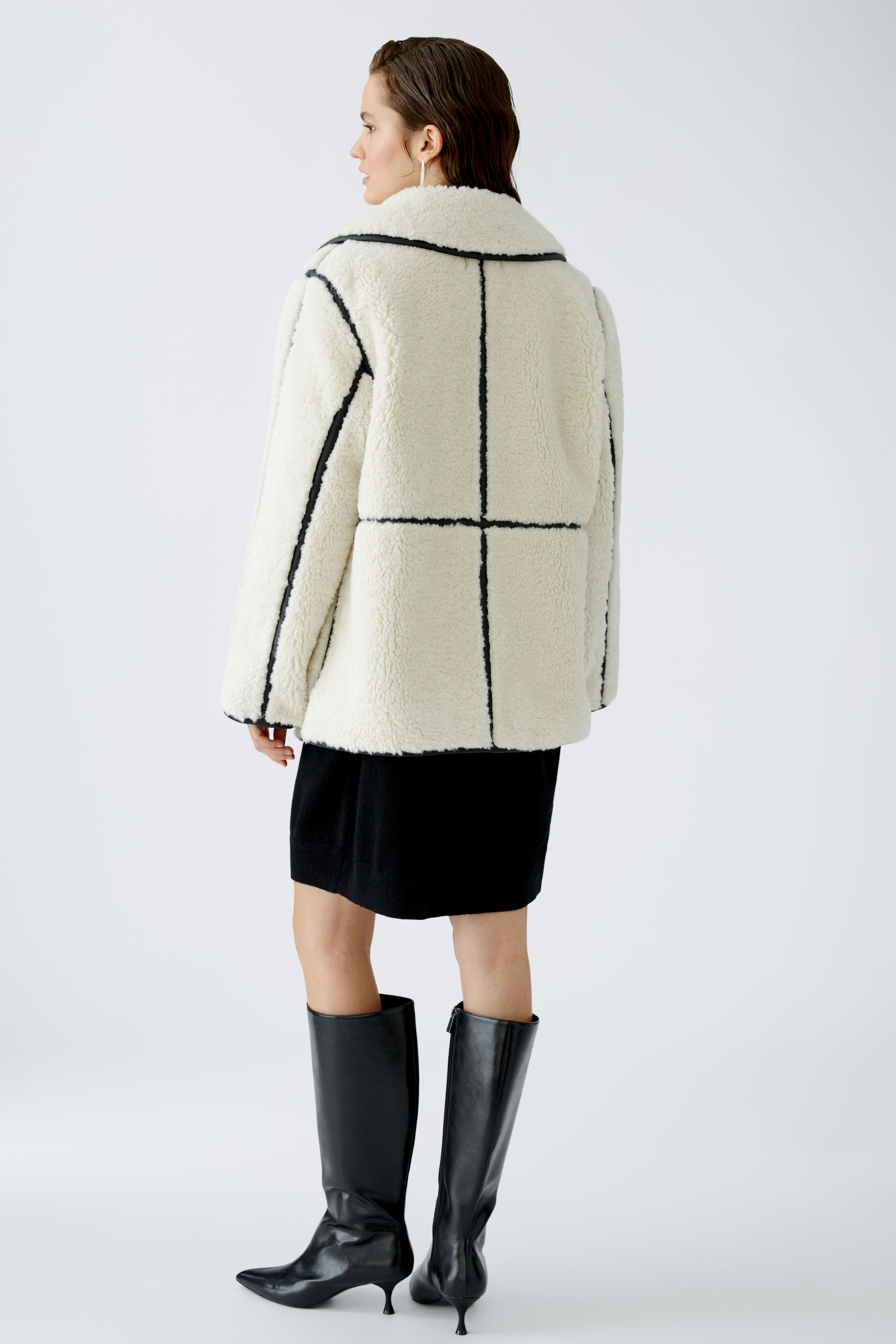 Feminine Outdoorjacke: Frau in einer weißen, gestreiften Jacke mit lässigem Schnitt und elegantem Look.