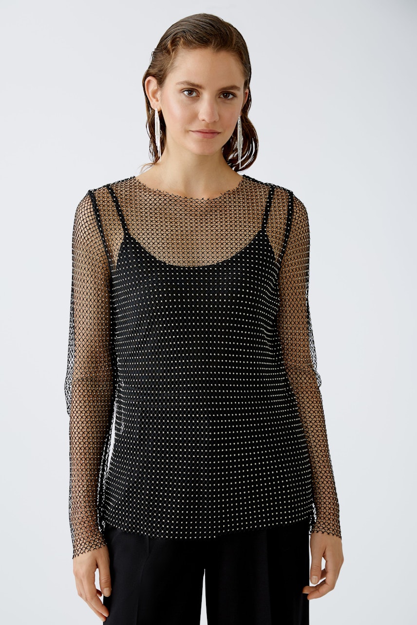 Chic long-sleeve shirt: Woman in a stylish black dotted top with a layered look.