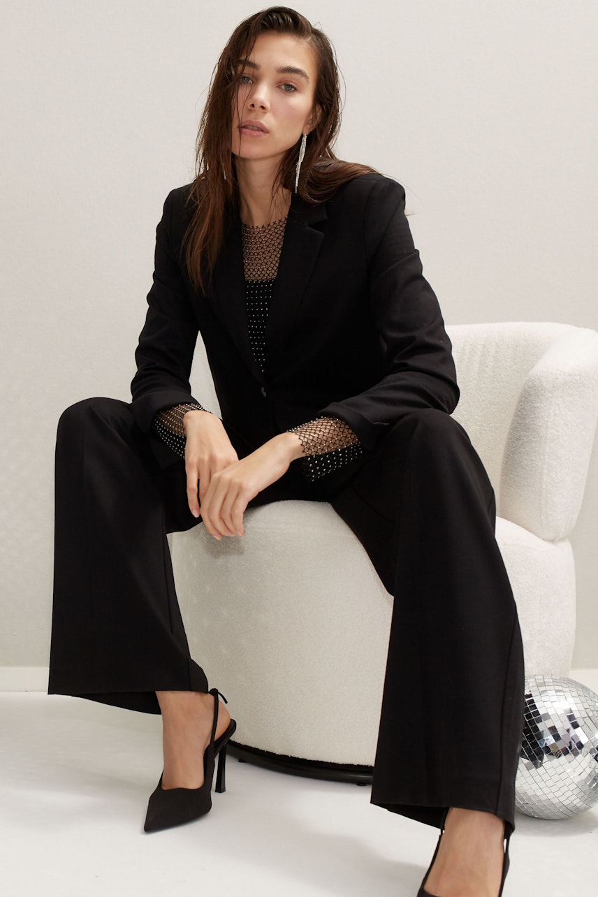 Chic long-sleeve shirt: Confident woman in a stylish black long-sleeve shirt, seated elegantly.