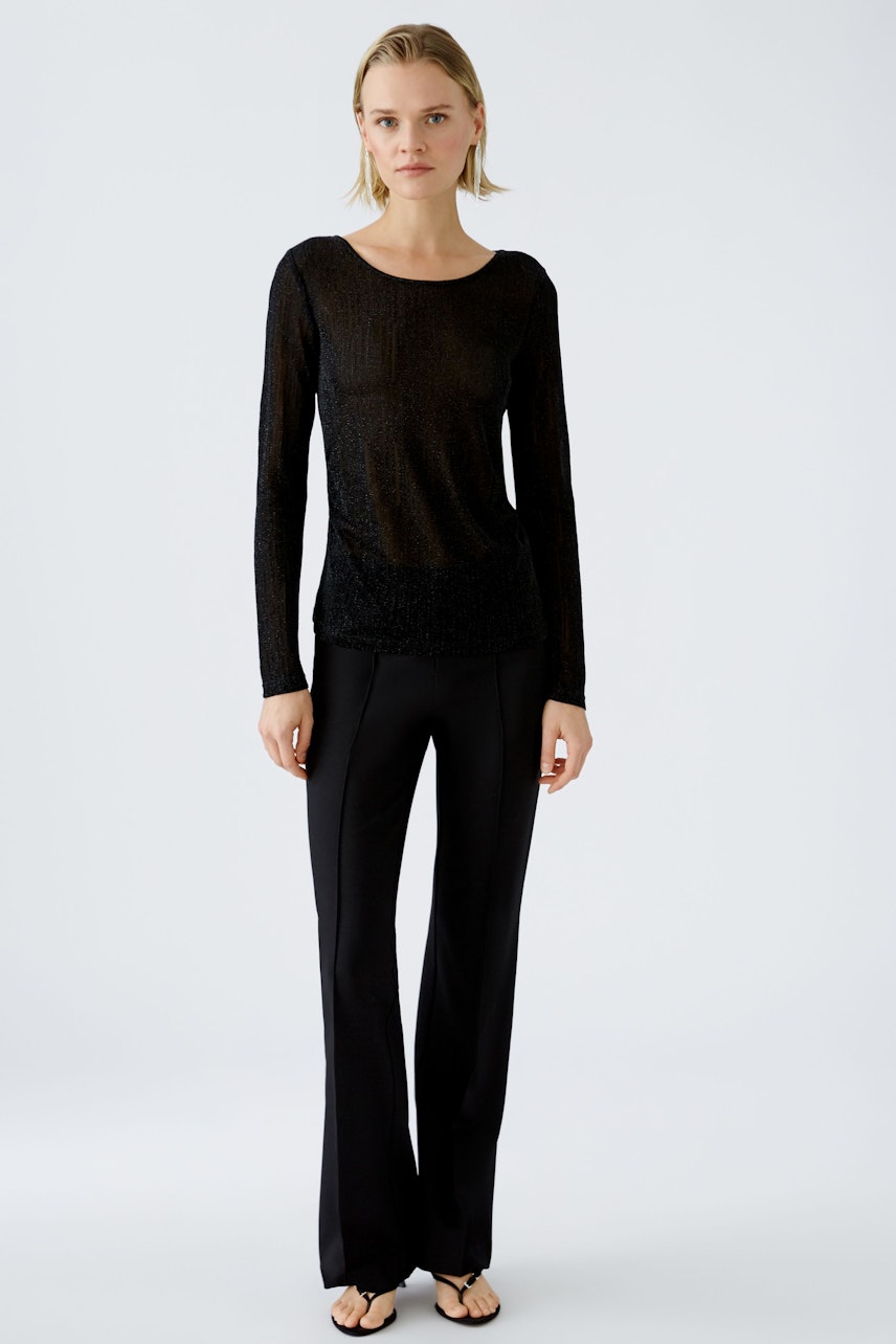 Elegant long-sleeve shirt: A woman in a black pullover paired with sleek trousers, exuding modern style.