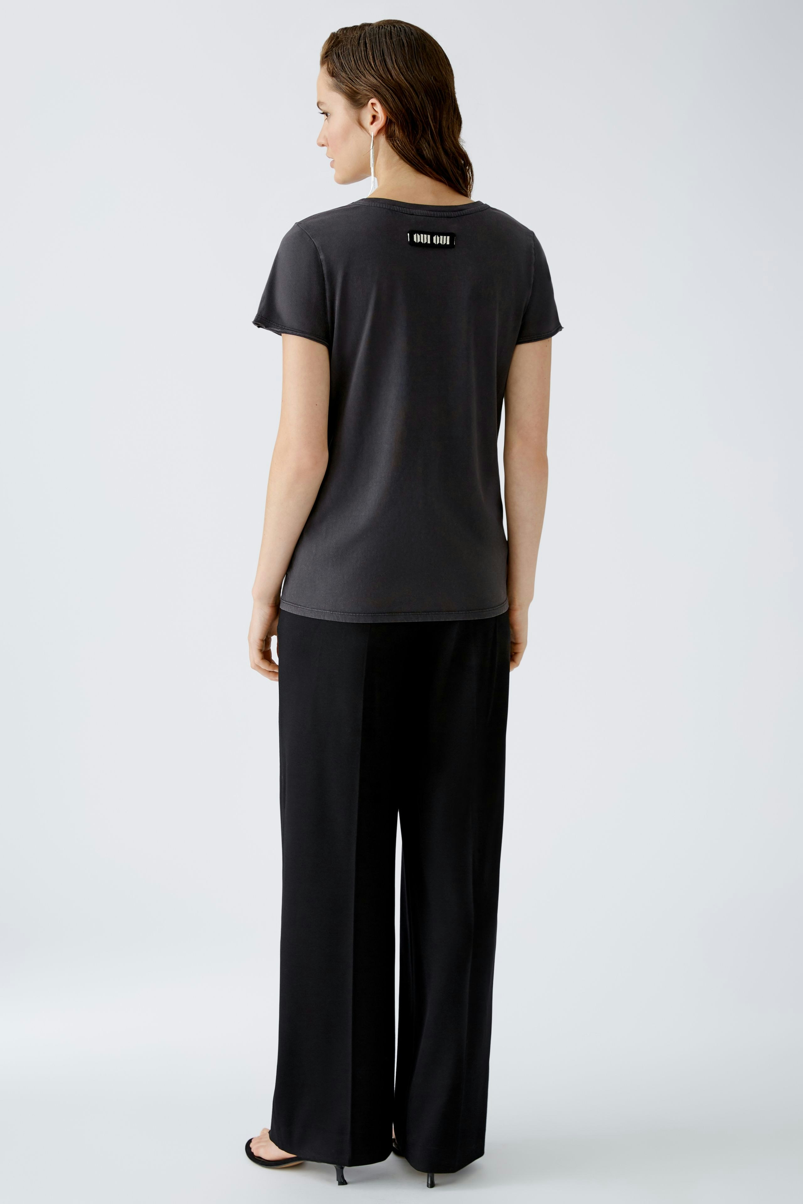 Stylish women's T-shirt: A woman in a dark gray tee paired with wide-leg pants, showcasing a modern look.