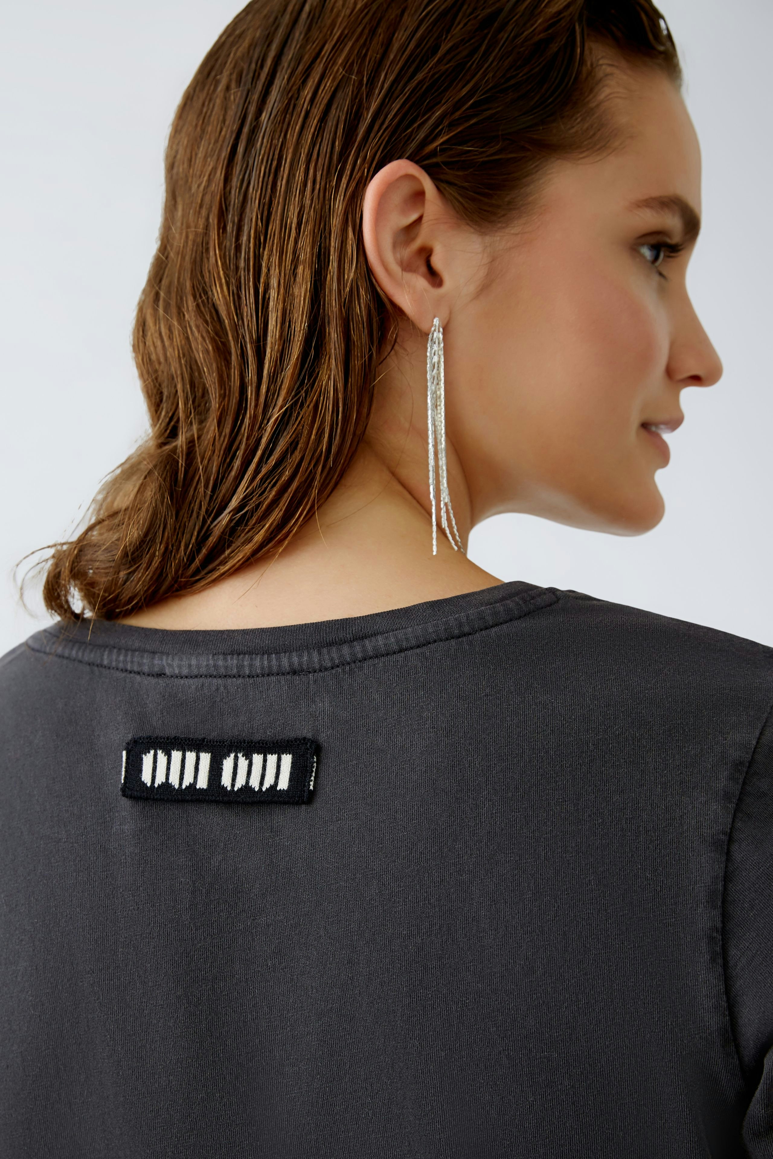 Stylish women's T-shirt: A woman in a sleek black T-shirt with a unique back detail.