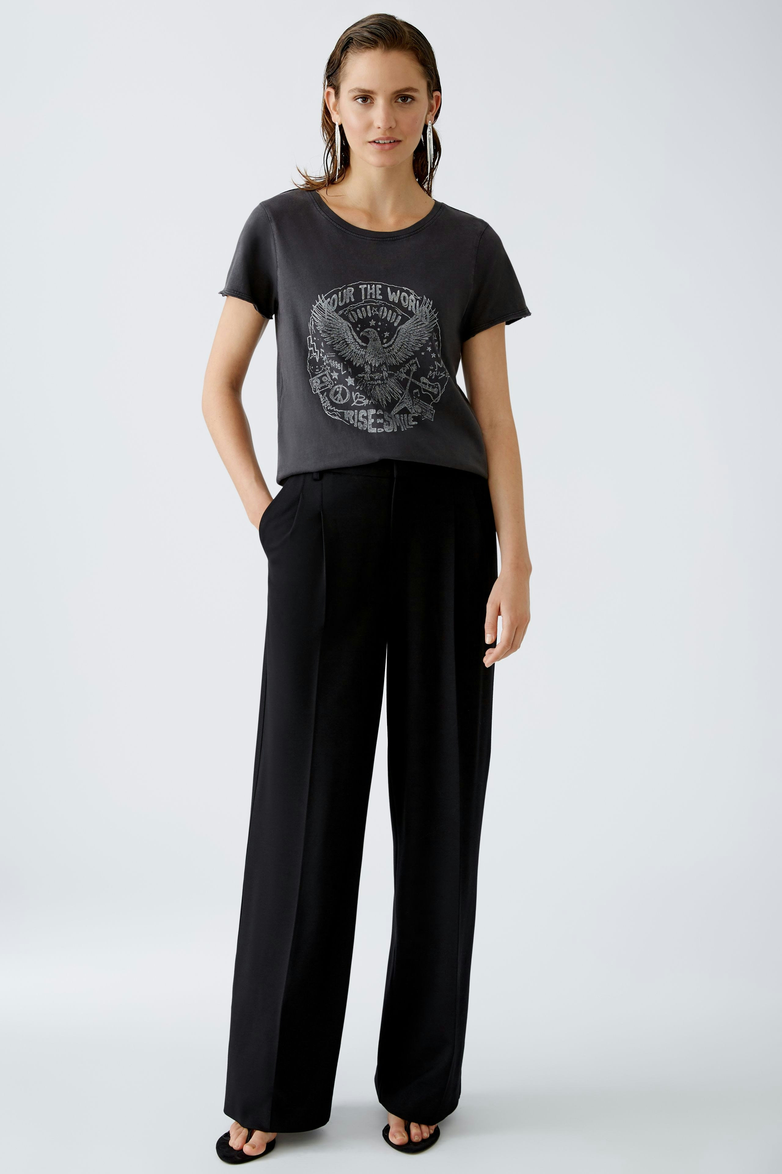 Casual women's T-shirt: Young woman in a gray graphic tee paired with black trousers, exuding effortless style.