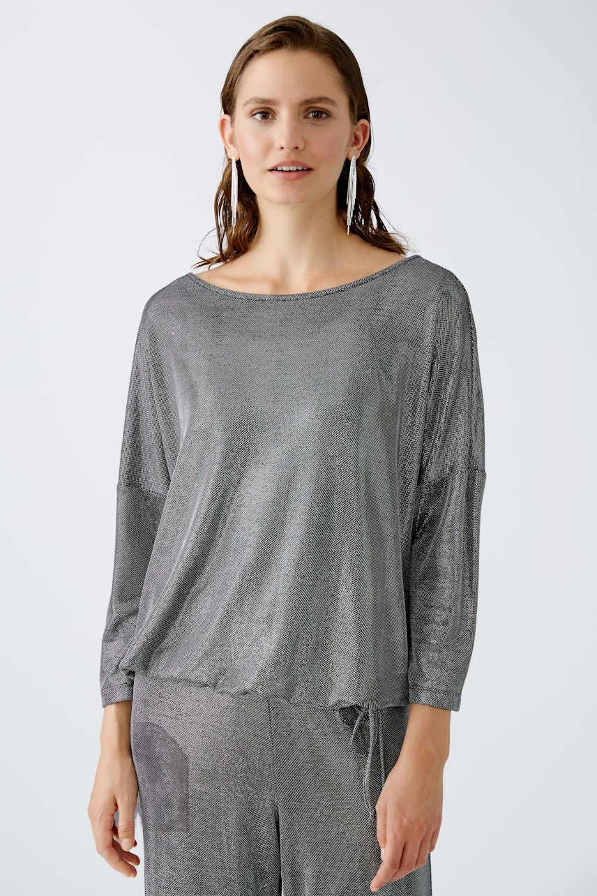 Stylish women's T-shirt: A woman in a shimmering gray top with a relaxed fit and elegant design.