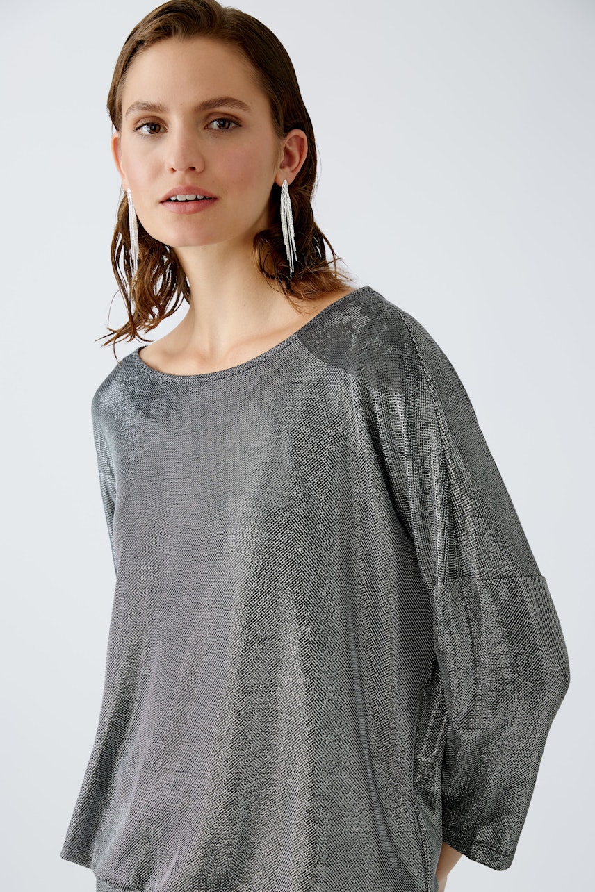 Stylish women's T-shirt: Woman in a shimmering gray top with a relaxed fit and elegant design.