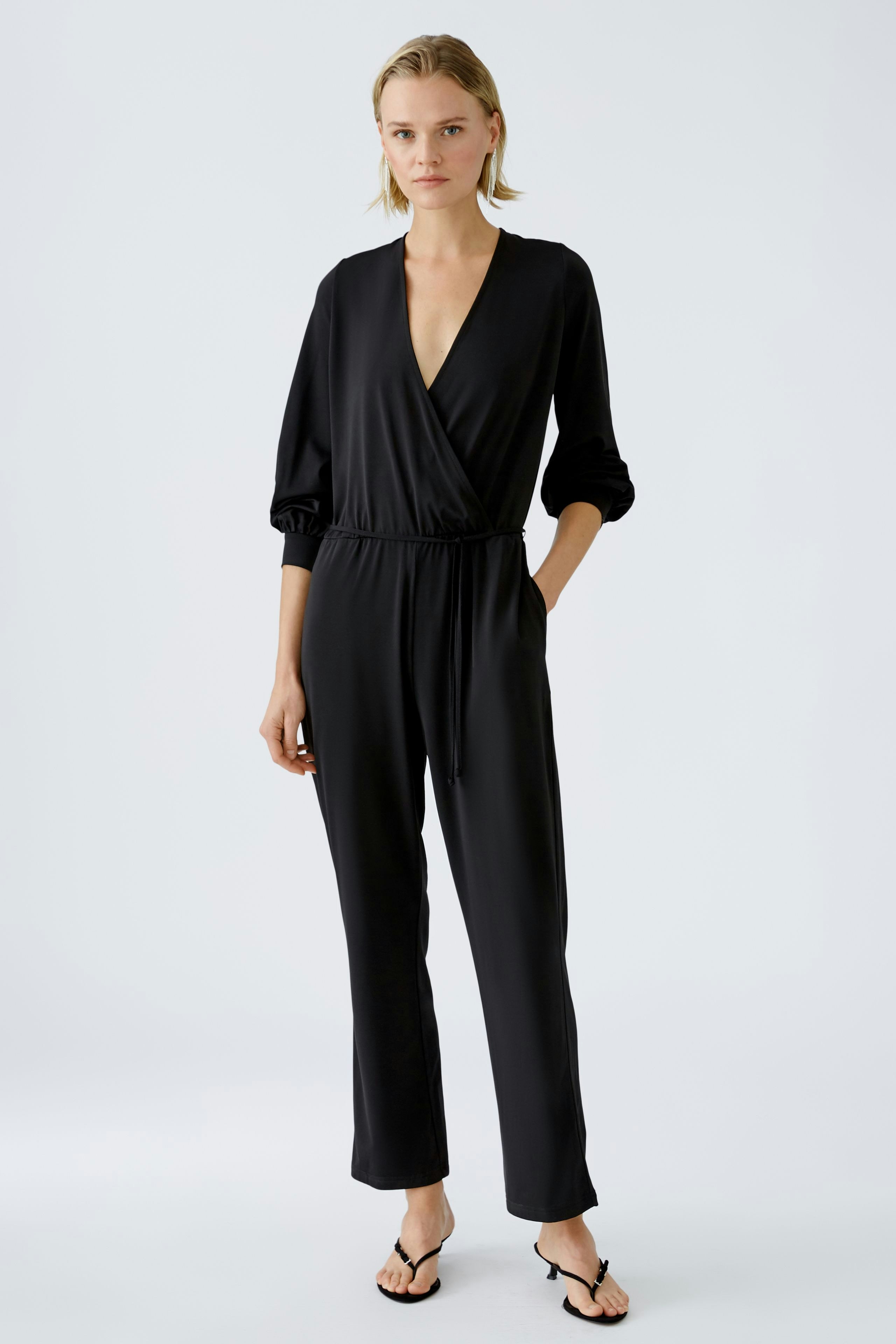 Elegant black jumpsuit: A woman in a stylish black jumpsuit with a deep V-neck and relaxed fit.
