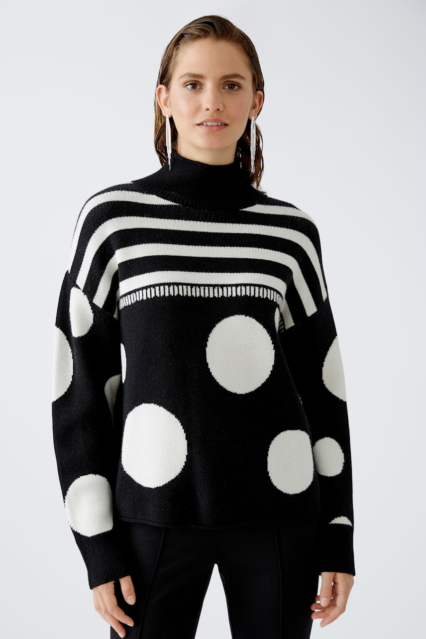 Modern pullover: Woman in a black and white striped pullover with polka dots, exuding confidence.