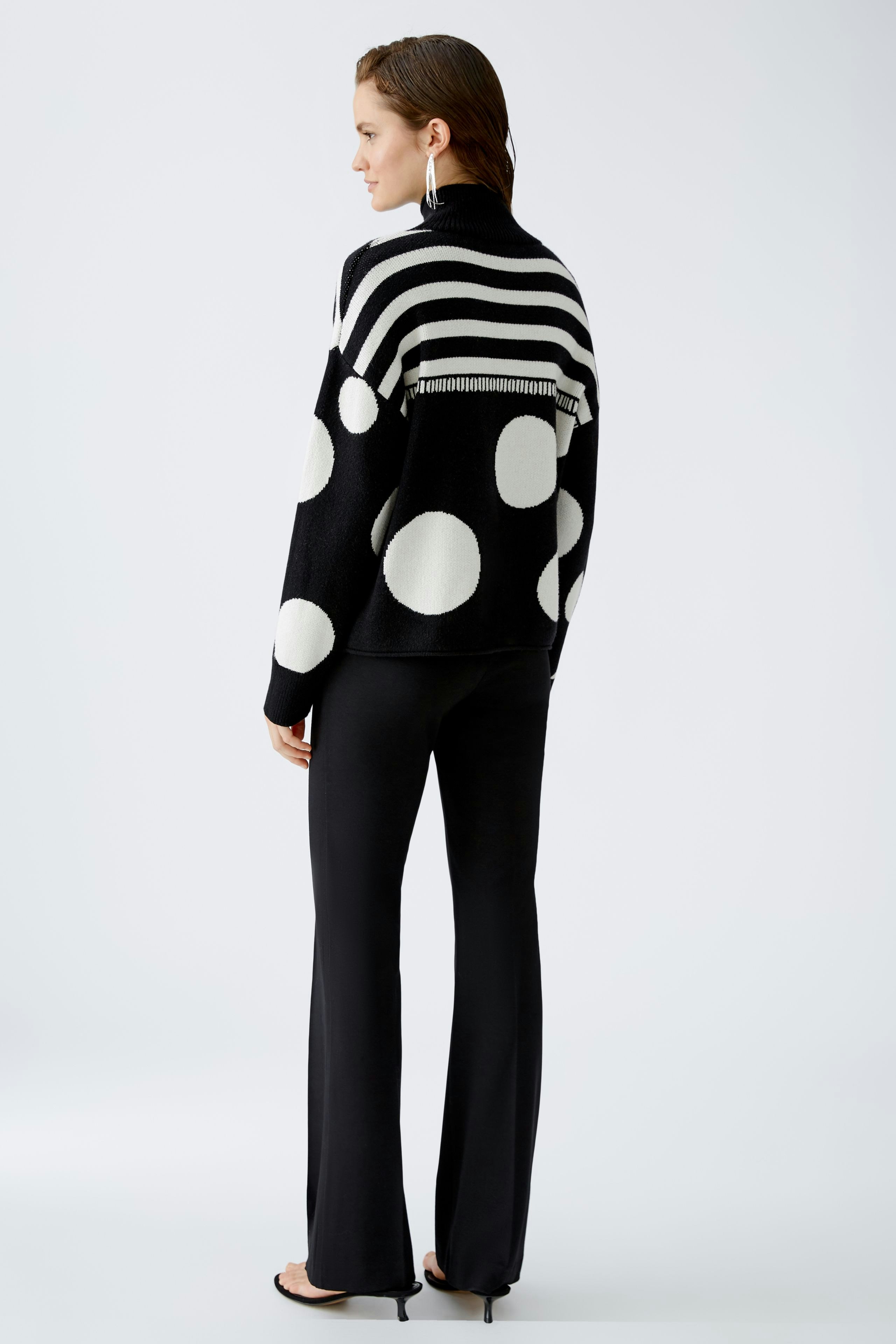 Stylish women's pullover: A woman in a black and white polka dot pullover with stripes, exuding confidence.