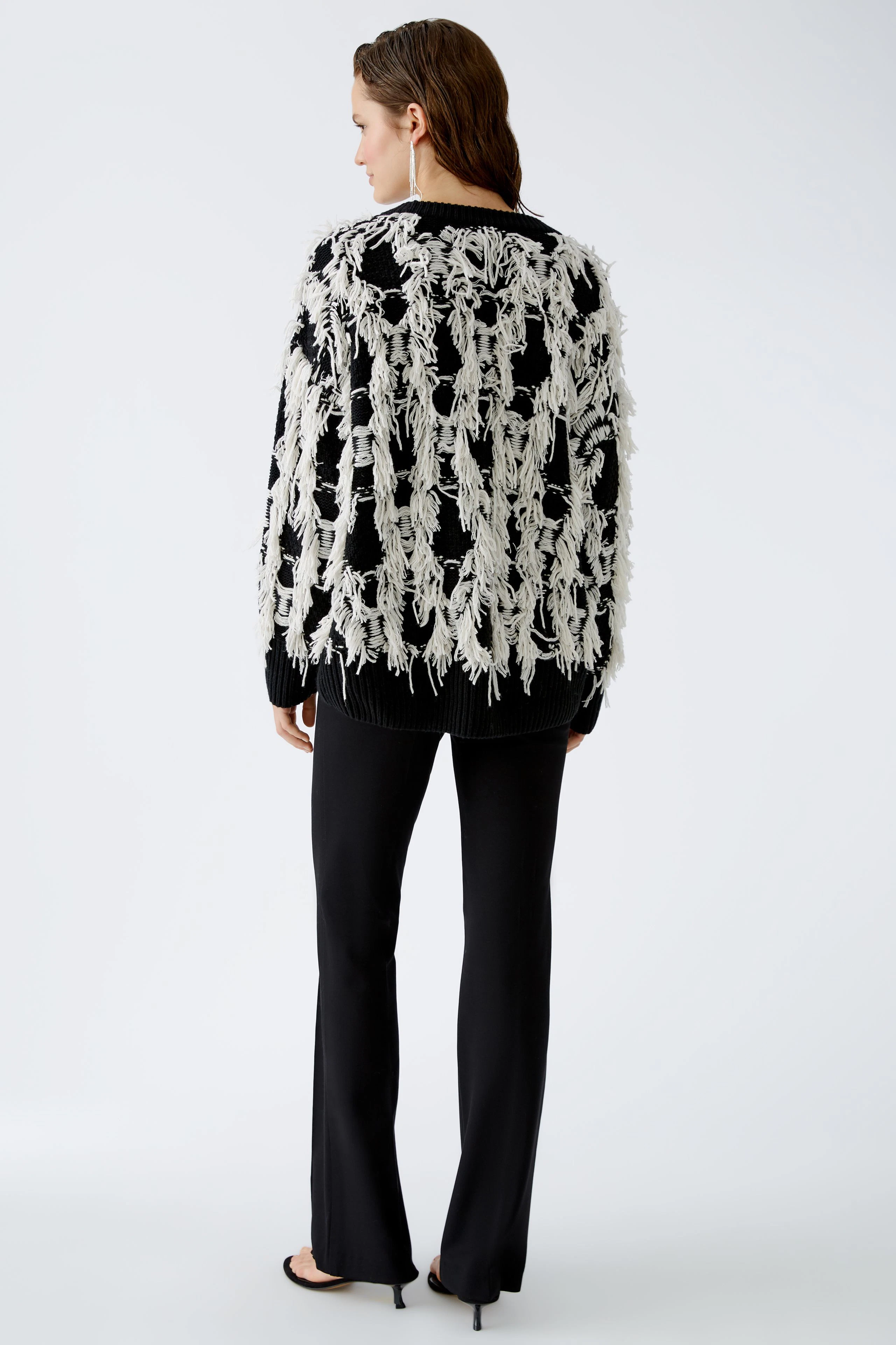 Stylish women's pullover: A woman in a black and white fringed pullover, exuding modern elegance.