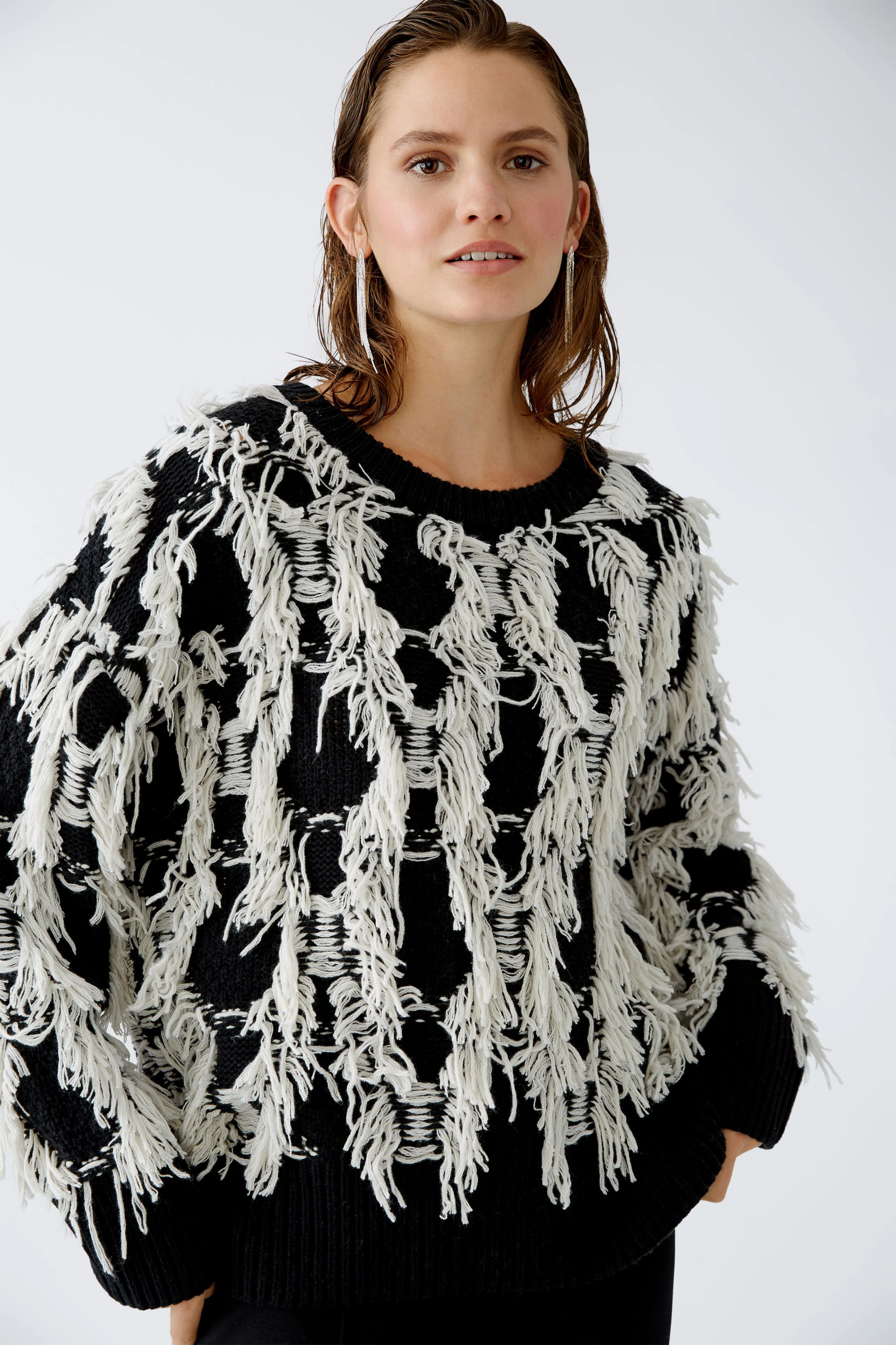 Modern women's pullover: A woman in a black and white fringed pullover, exuding confidence.