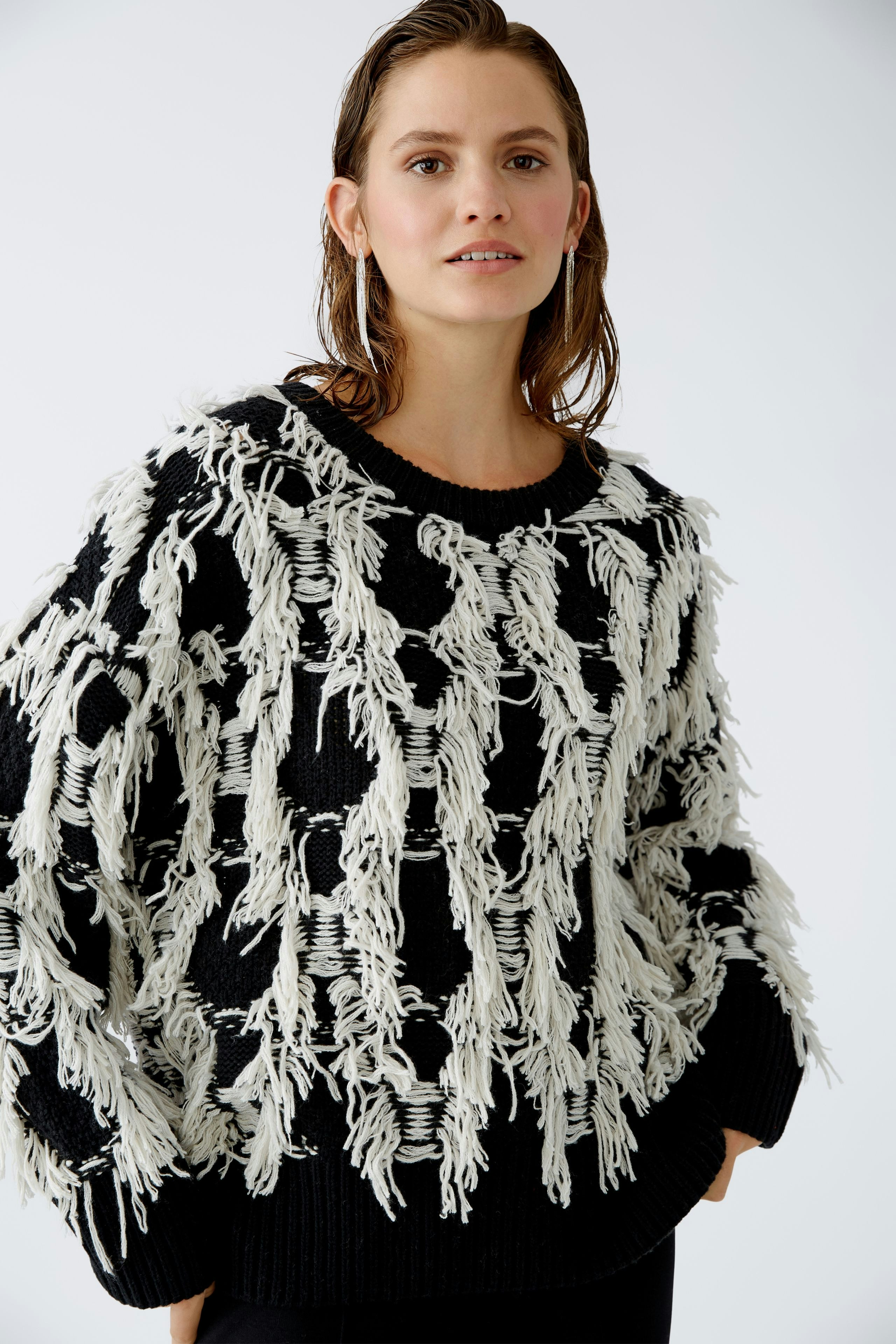 Modern women's pullover: A woman in a black and white fringed pullover, exuding confidence.