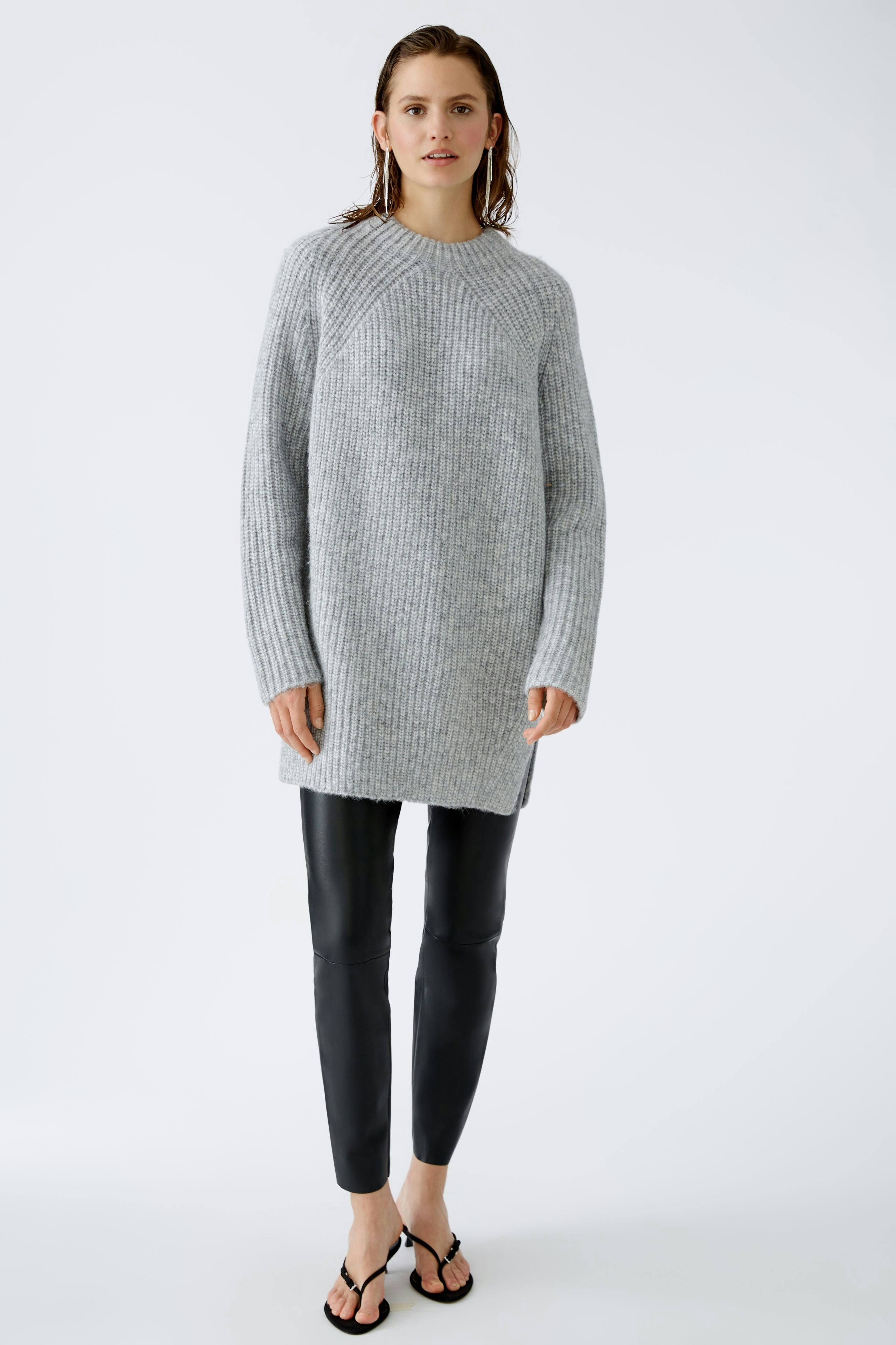 Modern women's pullover: A woman in a cozy gray pullover paired with sleek black leggings.