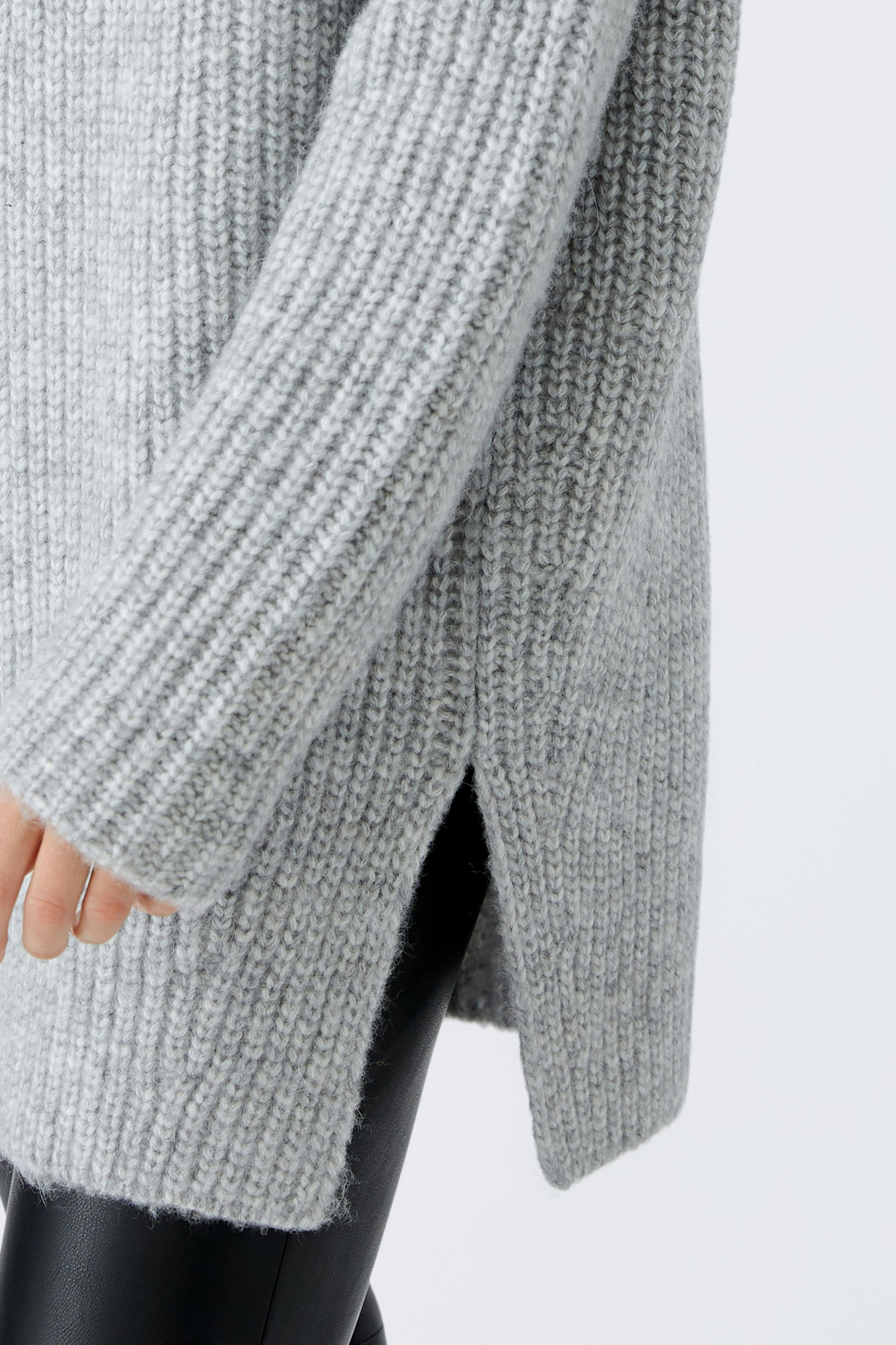 Stylish women's pullover: A woman showcases a cozy gray knit pullover with side slits.