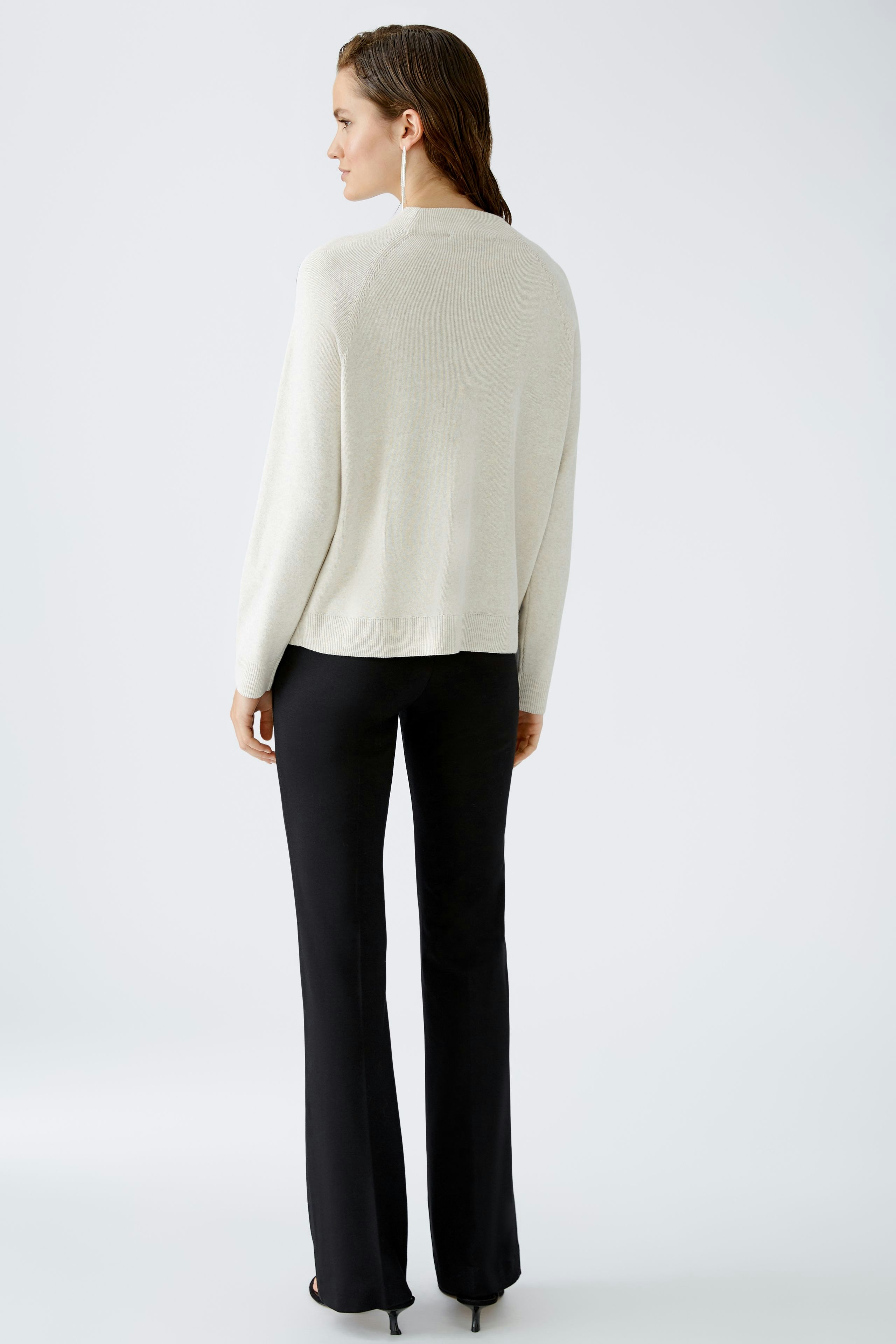 Stylish women's pullover: A woman in a cream pullover paired with black pants, showcasing a relaxed look.