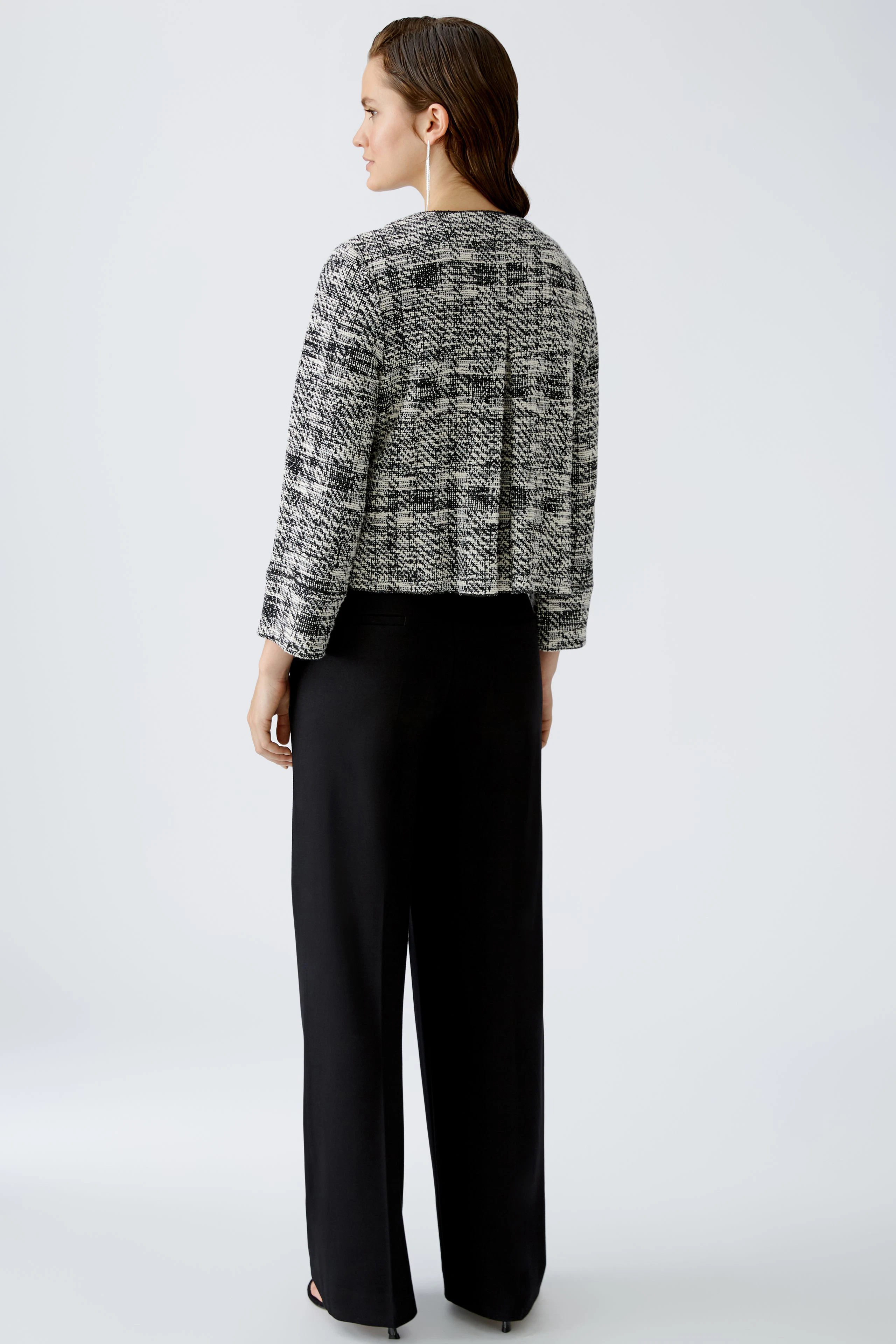 Eleganter Blouson: Frau in modischem, strukturiertem Blouson mit lässigem Schnitt und schwarzer Hose.