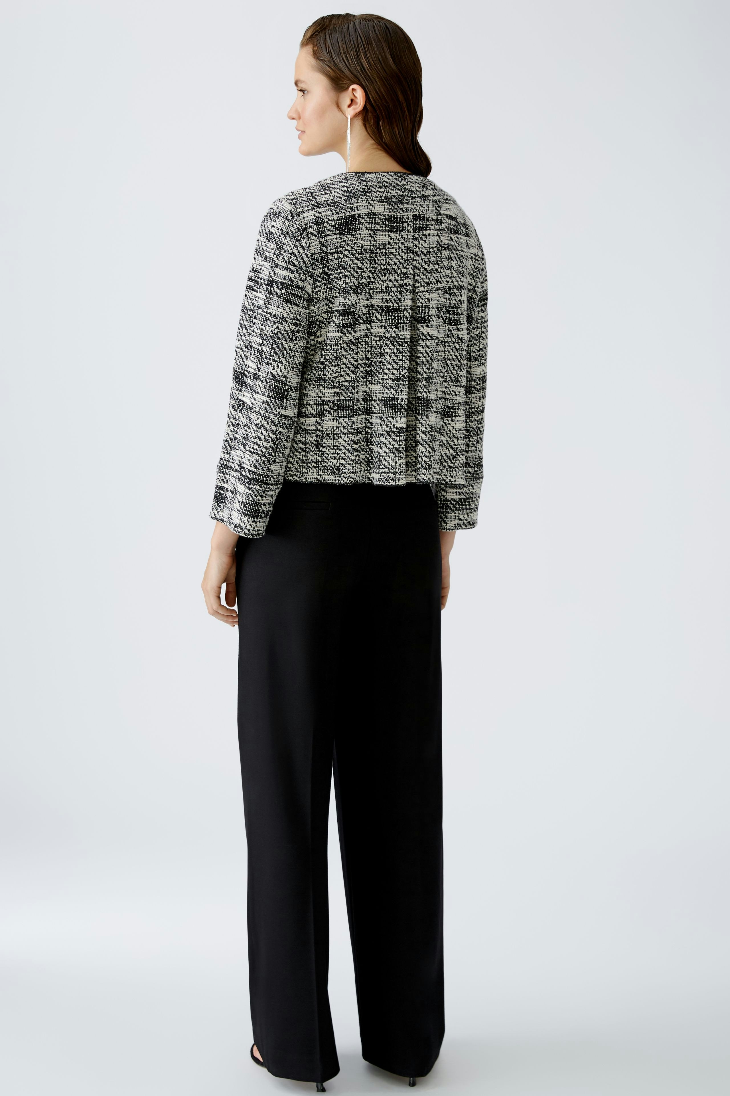 Eleganter Blouson: Frau in modischem, strukturiertem Blouson mit lässigem Schnitt und schwarzer Hose.