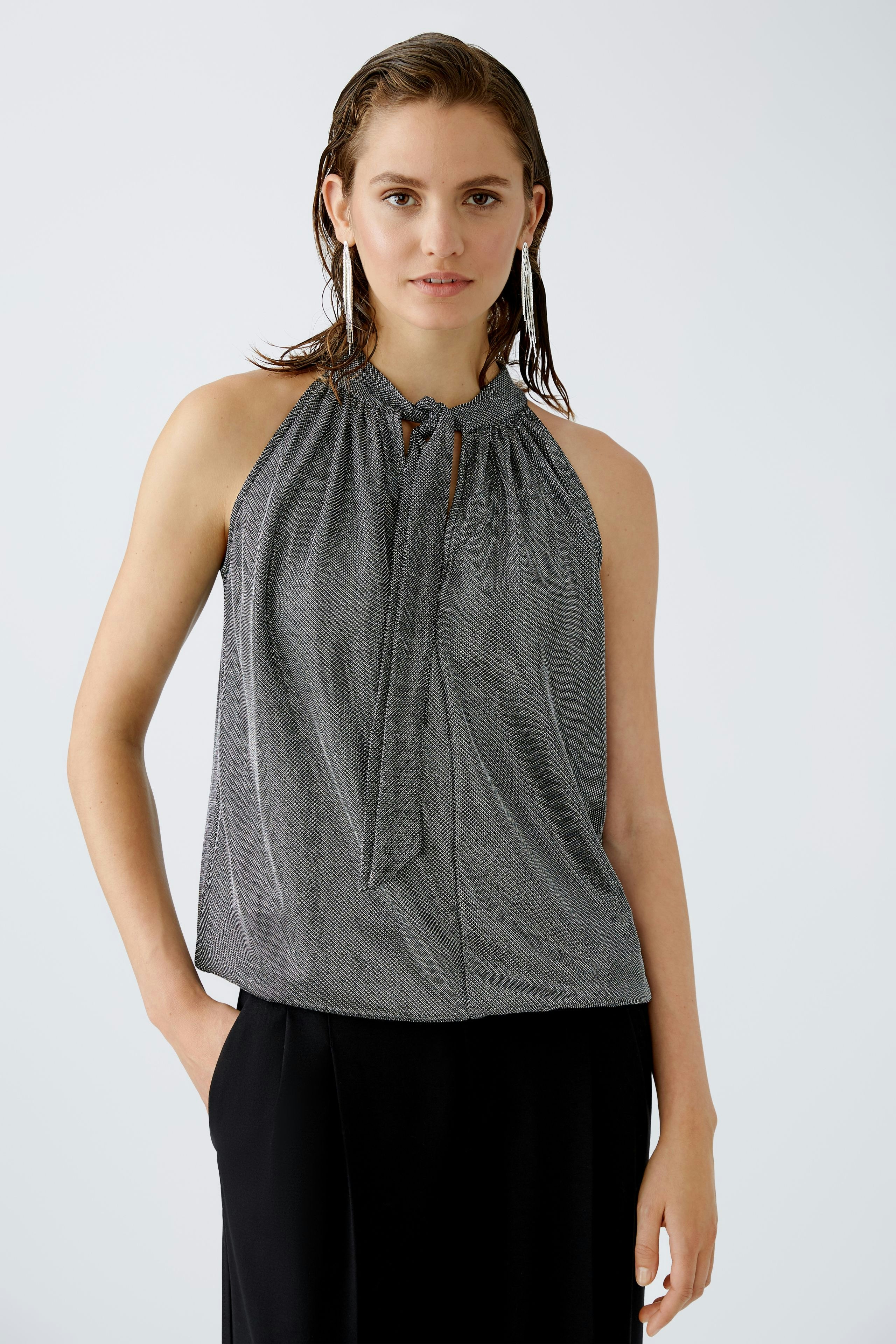 Elegantes Damen-Top: Frau in schimmerndem, grauem Top mit Bindeband und lässiger Ausstrahlung.